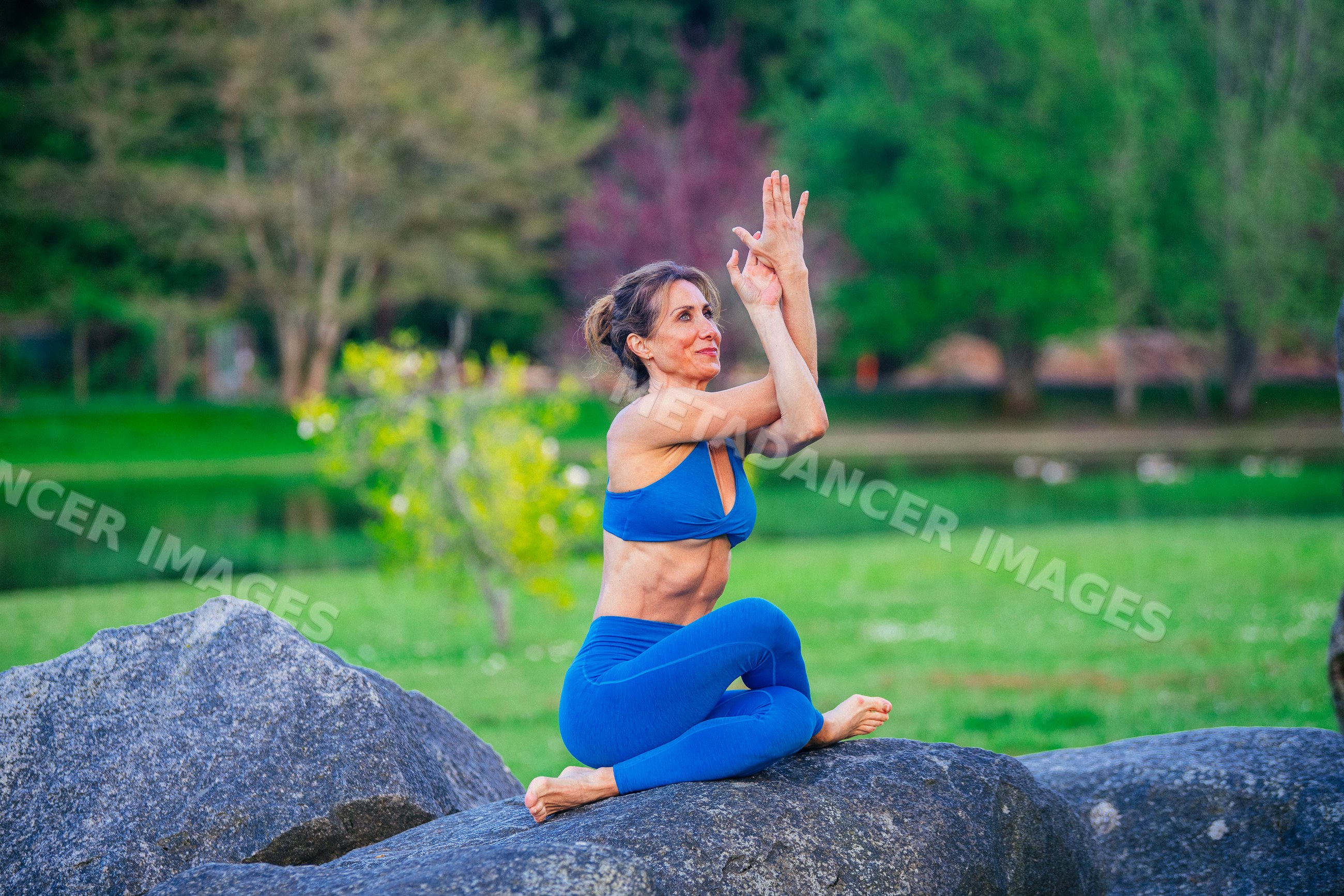 White woman practicing yoga on a rock