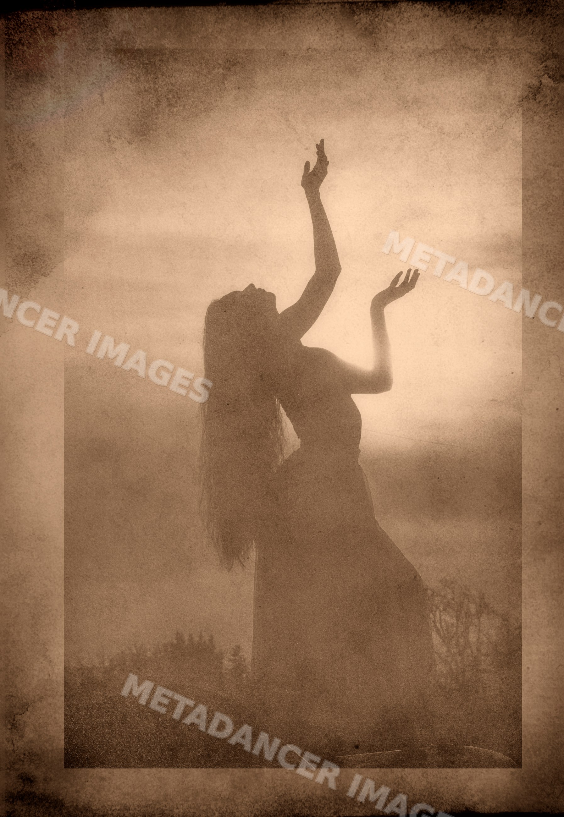 Silhouette of white woman dancing outdoors at sunset in sepia tone