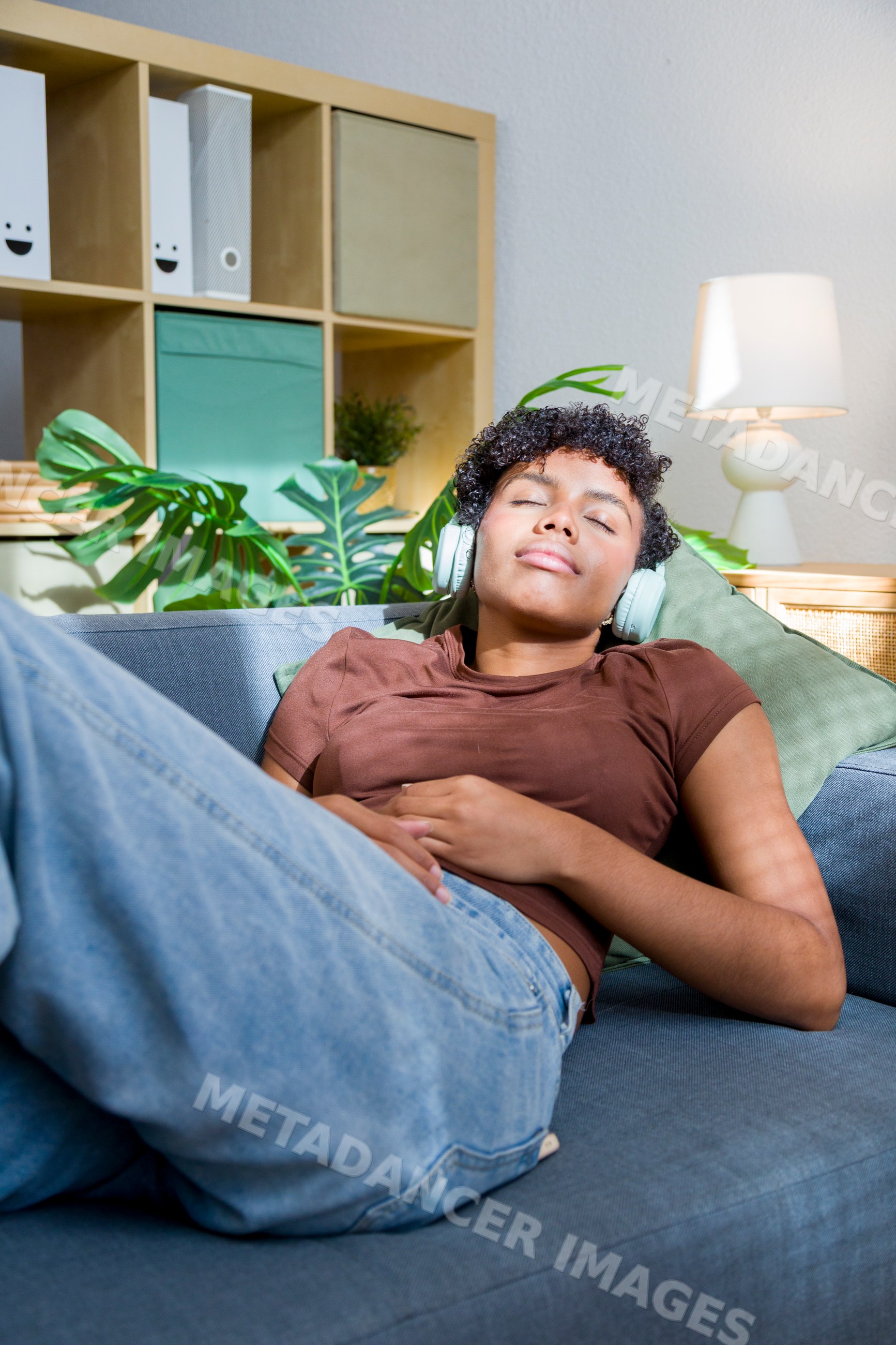 Young African American woman relaxing on couch listening to music