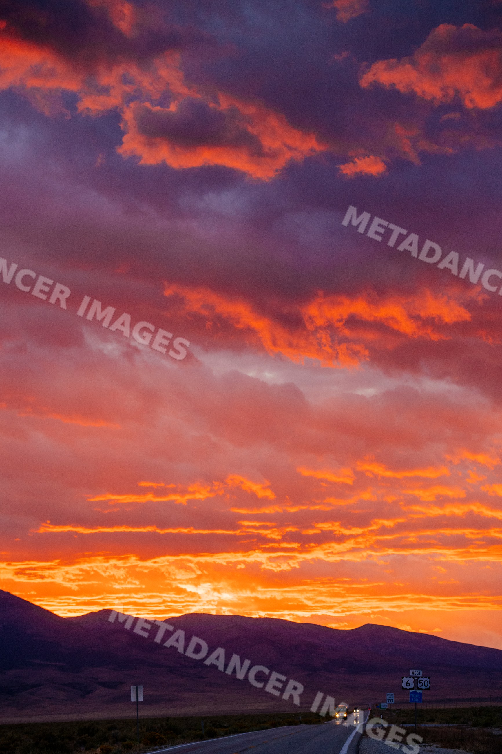 Sunset over Nevada mountains and highway with vehicles and dramatic