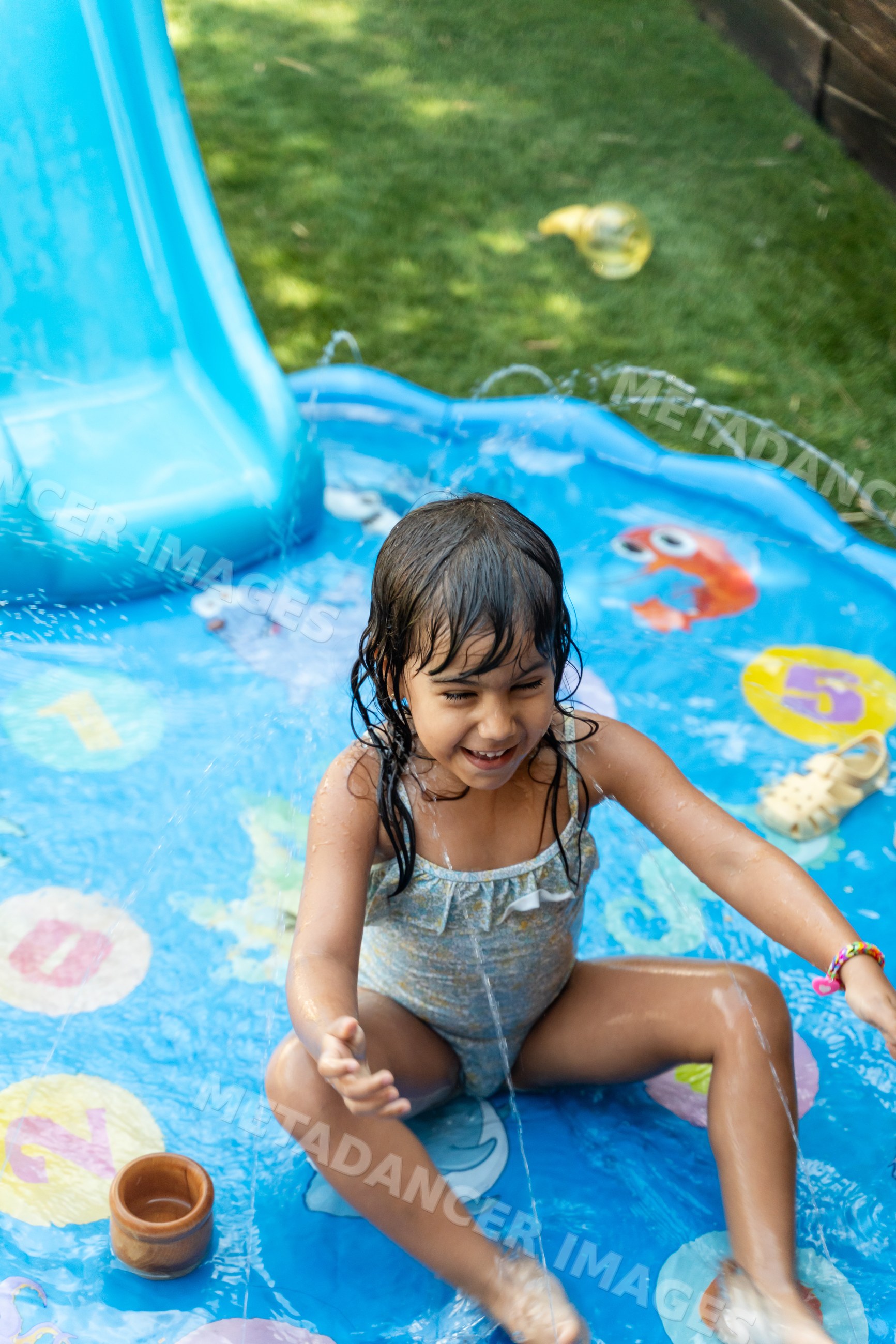A white girl playing and splashing water in a backyard inflatable pool