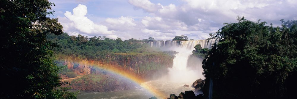 Iguacu falls with rainbow over river lush forest landscape