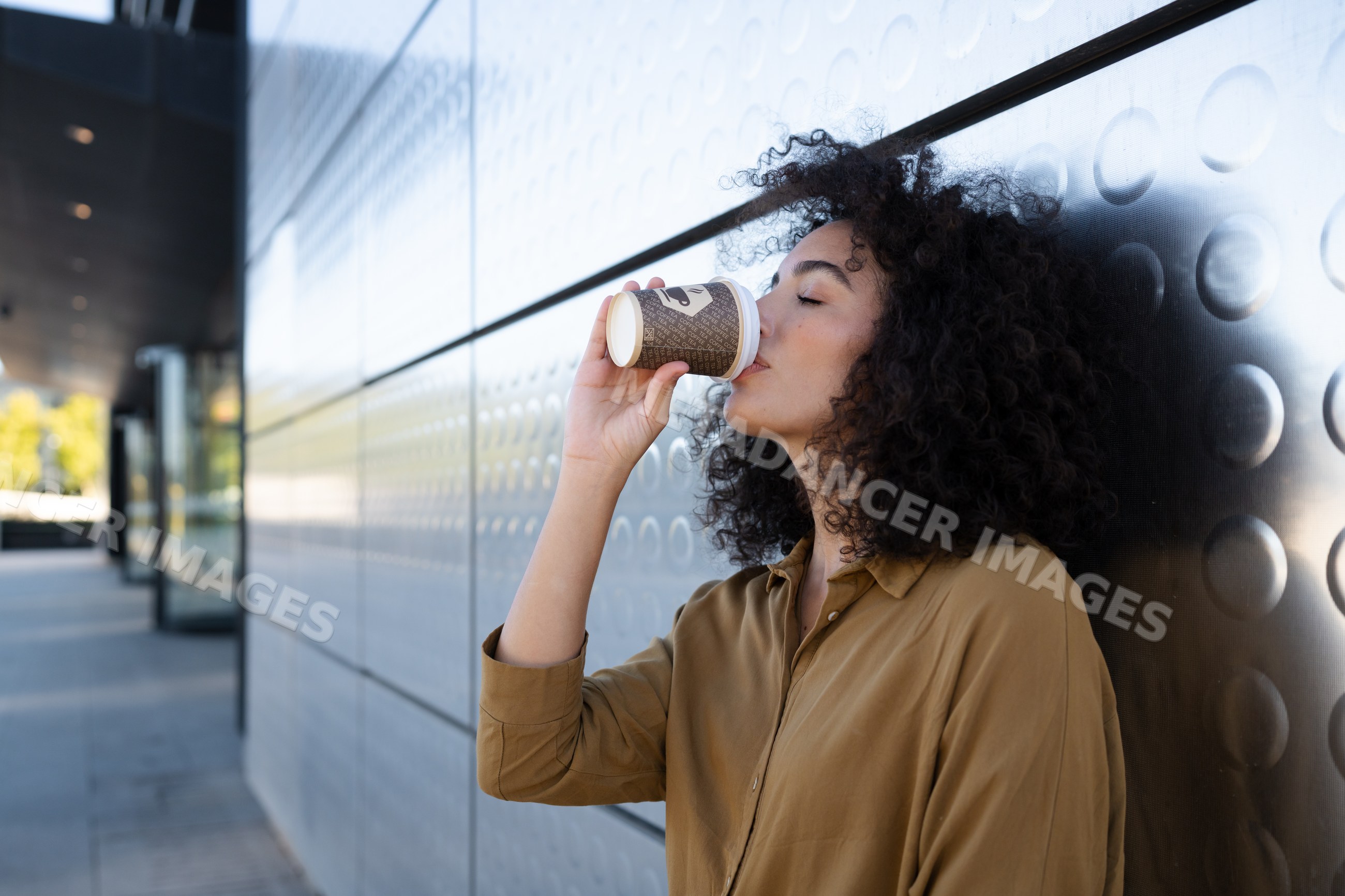 Woman drinking coffee from paper cup on urban sidewalk
