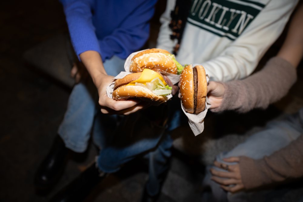 Hispanic, white and Black people holding cheeseburgers and burgers