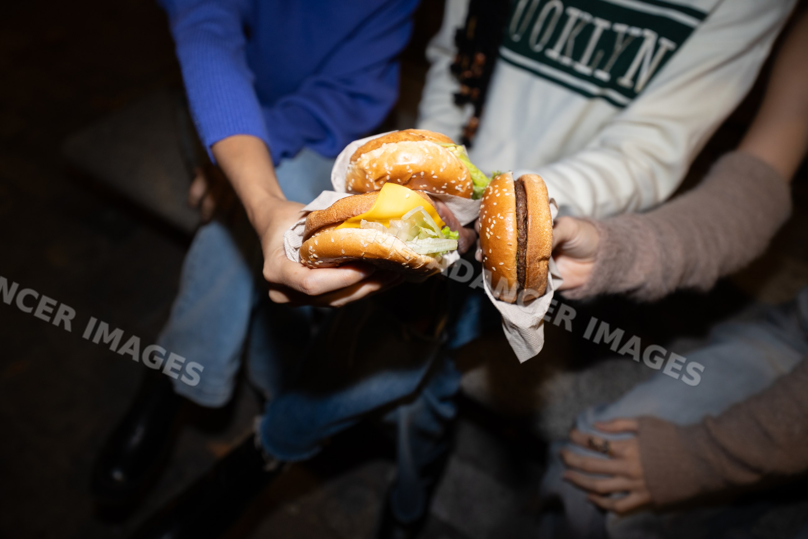 Hispanic, white and Black people holding cheeseburgers and burgers