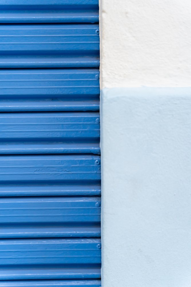 Blue metal shutter beside white painted textured wall