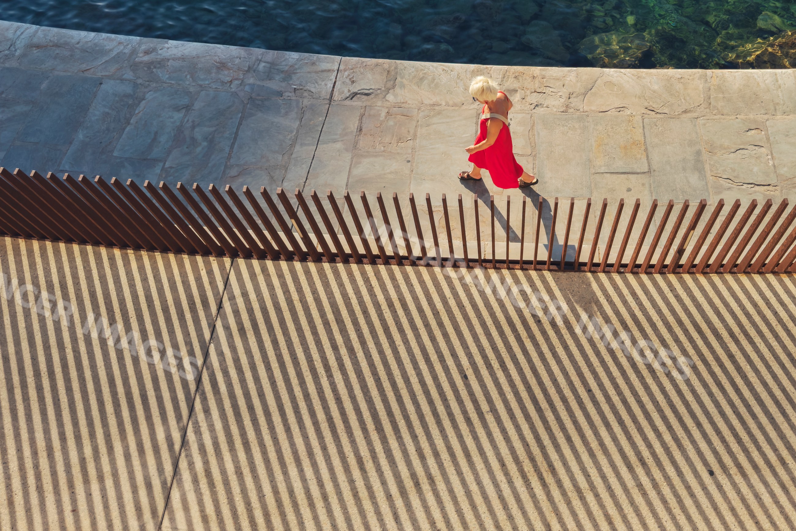 Woman walking on breakwater with shadows in bastia corsica