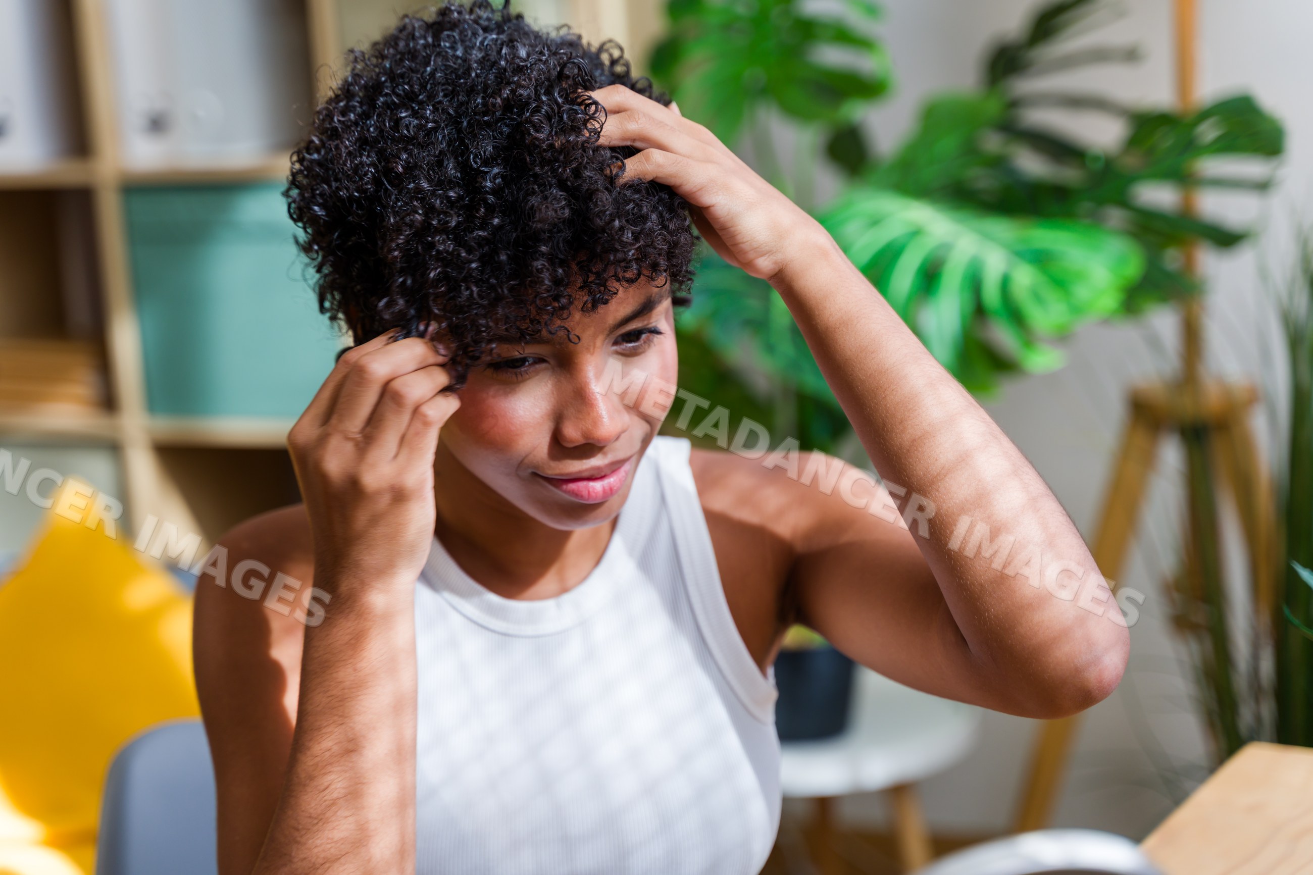 Young African American woman adjusting curly black hair indoors