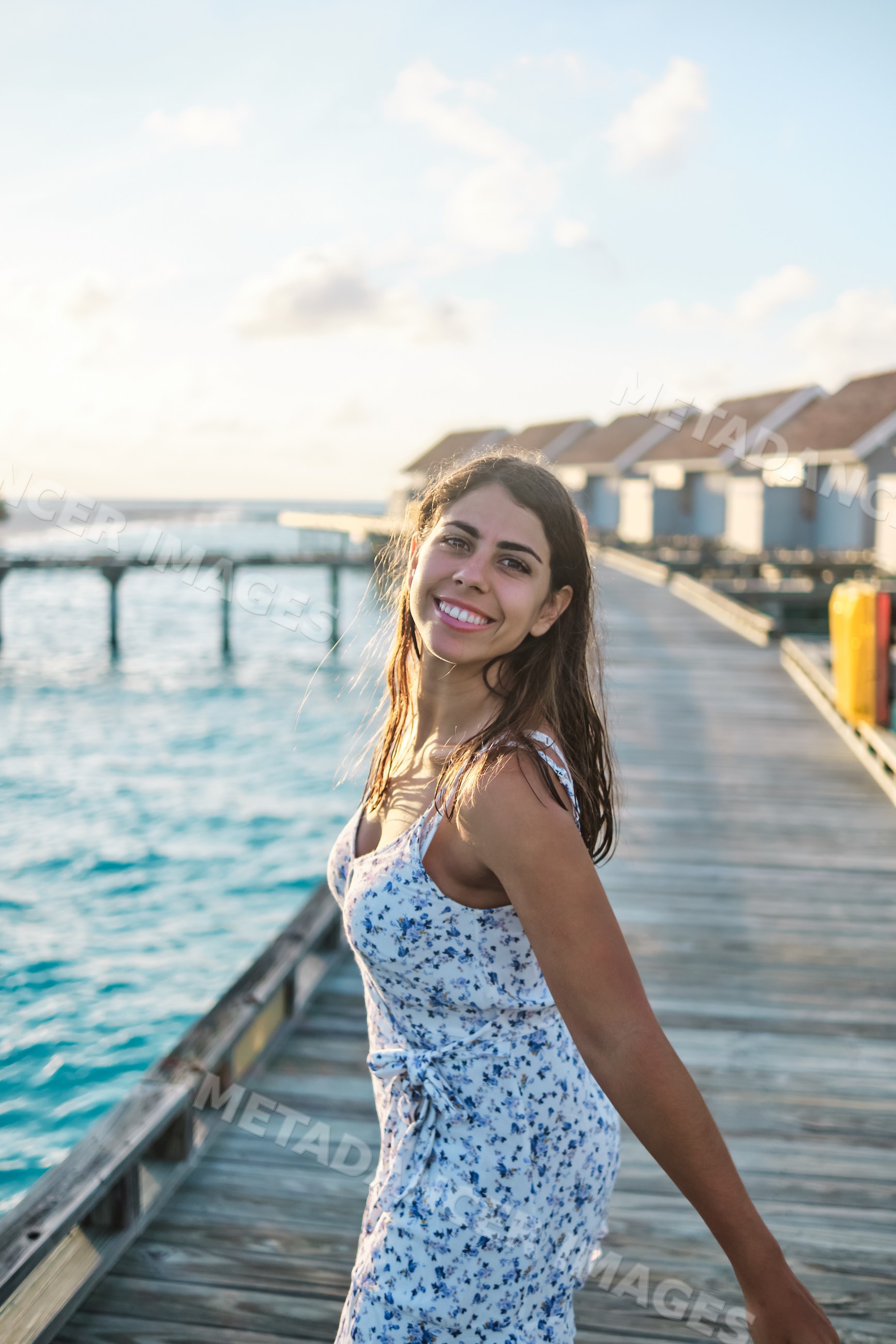 A young white woman enjoys a sunny day on a wooden pier