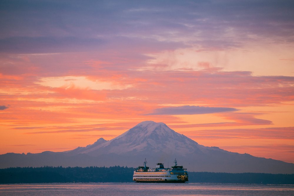 Ferry on calm water at sunset with mount rainier in the background