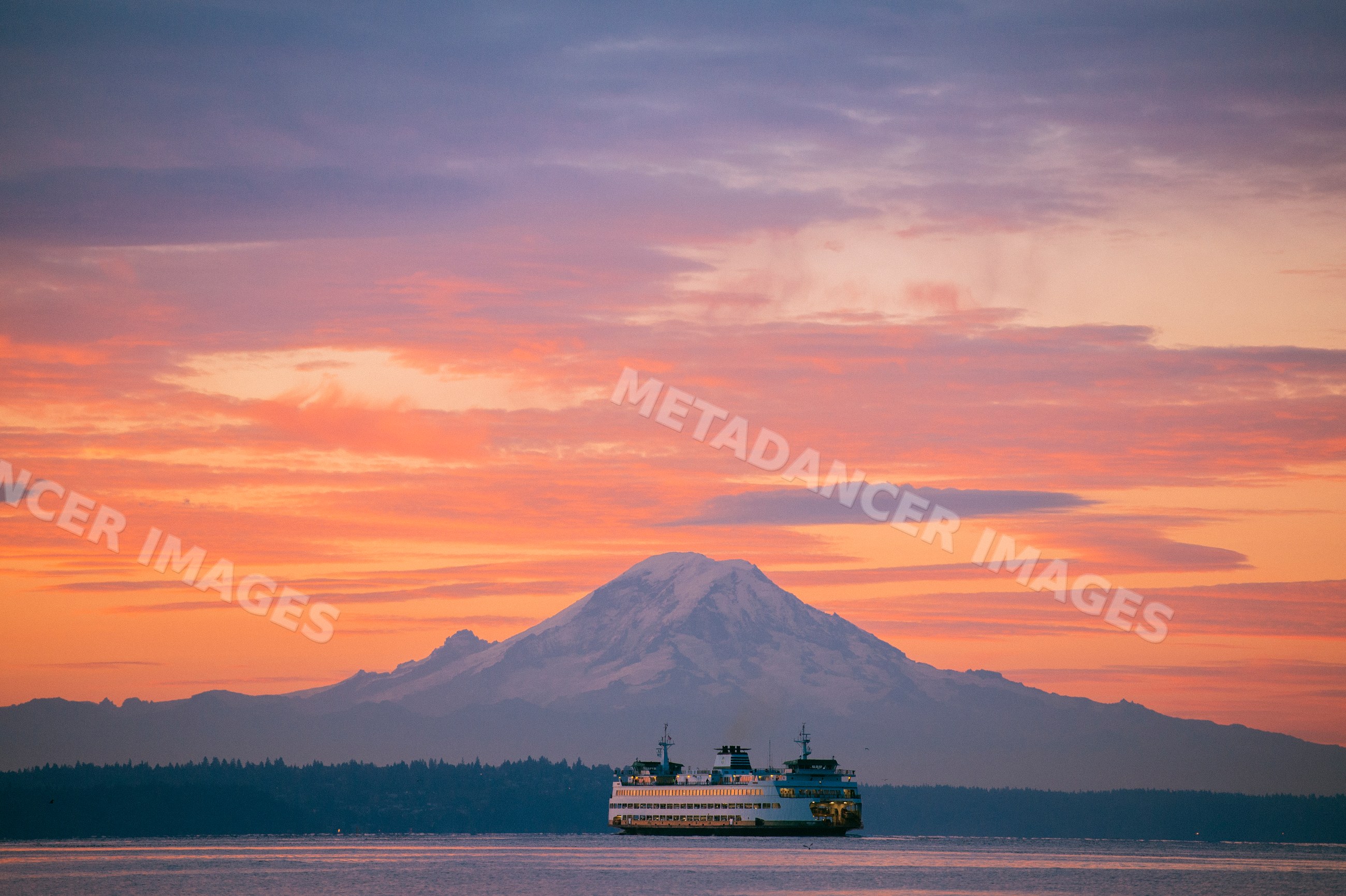 Ferry on calm water at sunset with mount rainier in the background