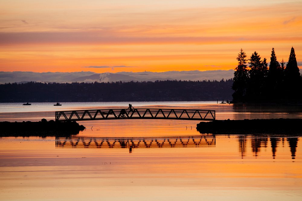 Sunset with Pacific Islander person on bicycle crossing bridge