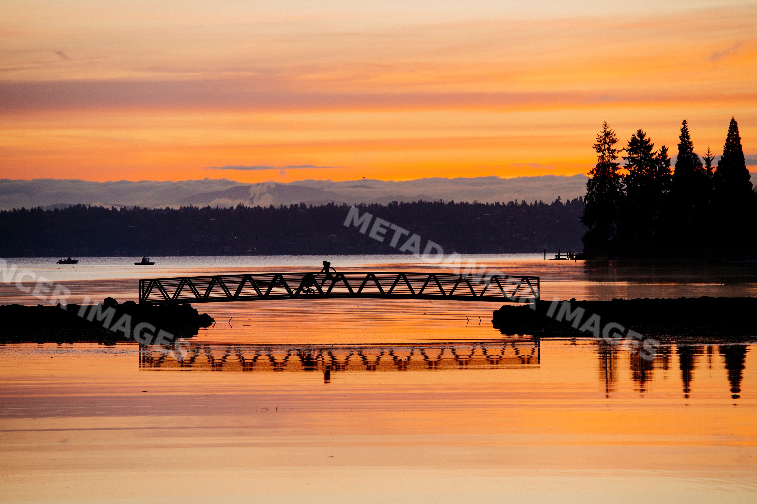 Sunset with Pacific Islander person on bicycle crossing bridge