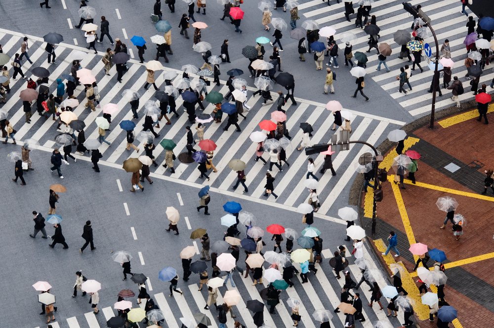 Pedestrians crossing shibuya intersection with umbrellas
