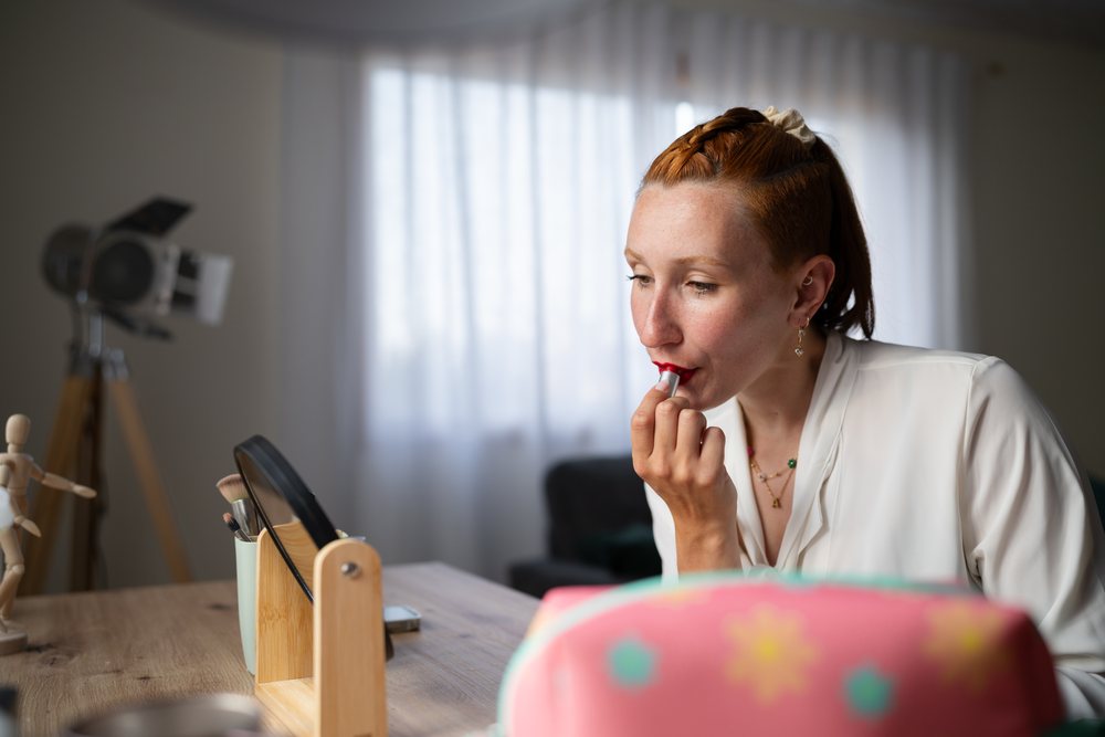 A white woman applies red lipstick