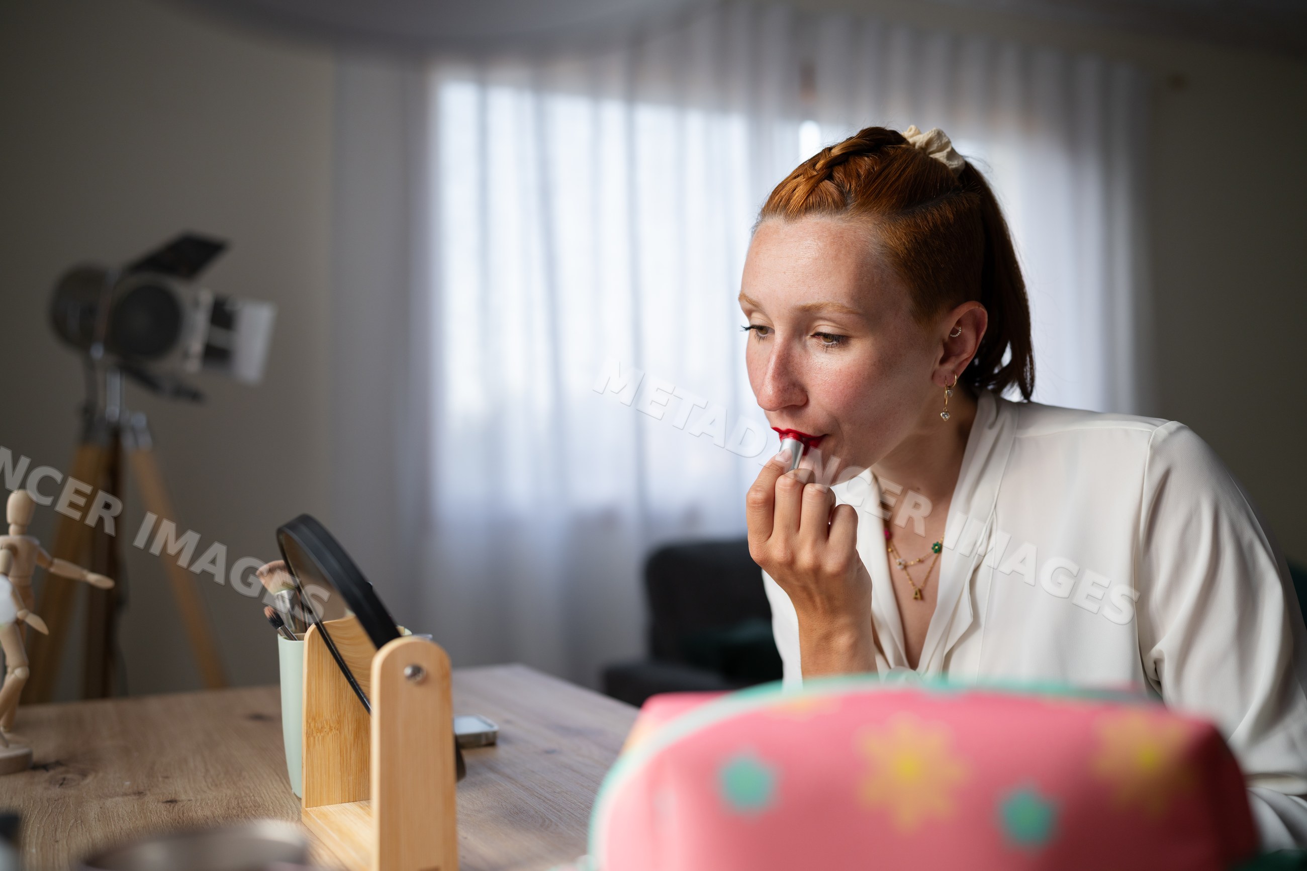 A white woman applies red lipstick