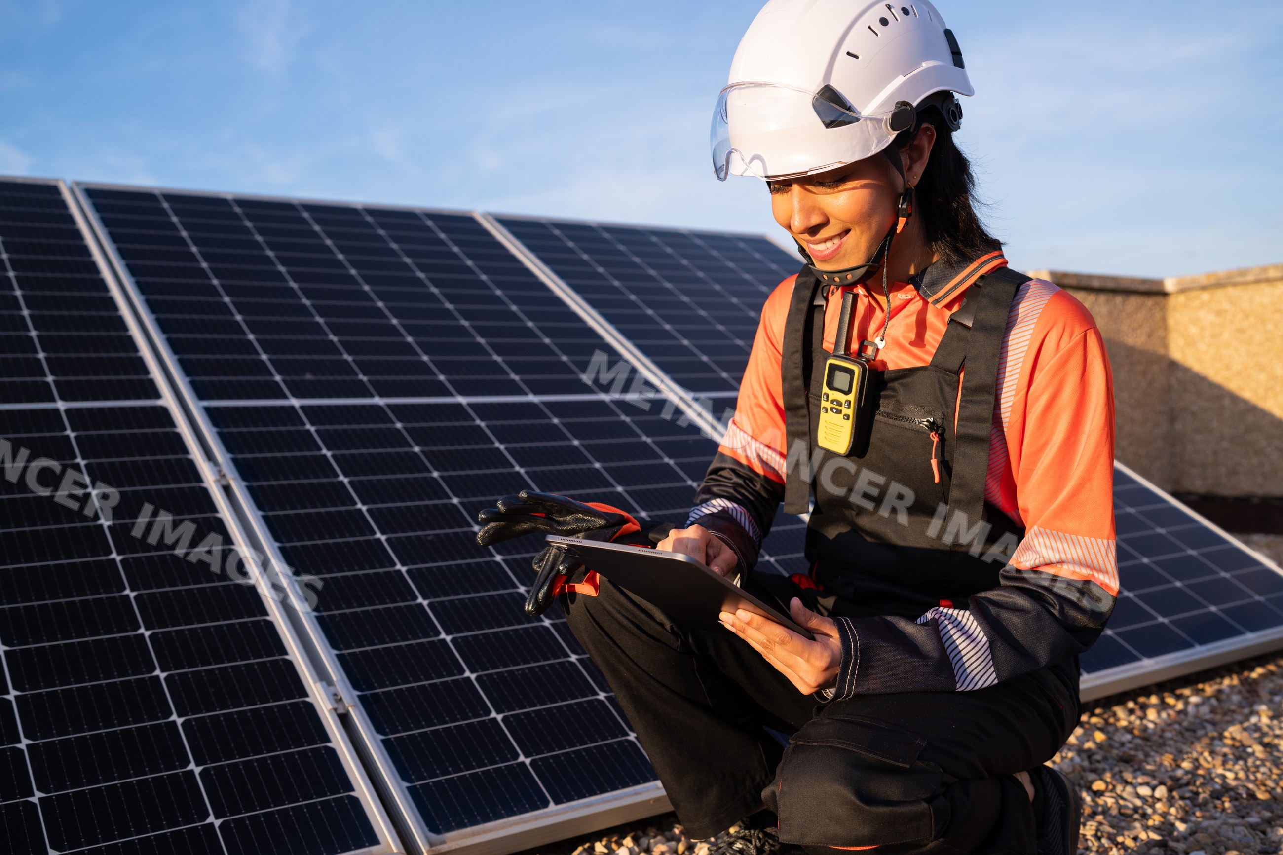Hispanic woman solar energy technician using tablet to check solar