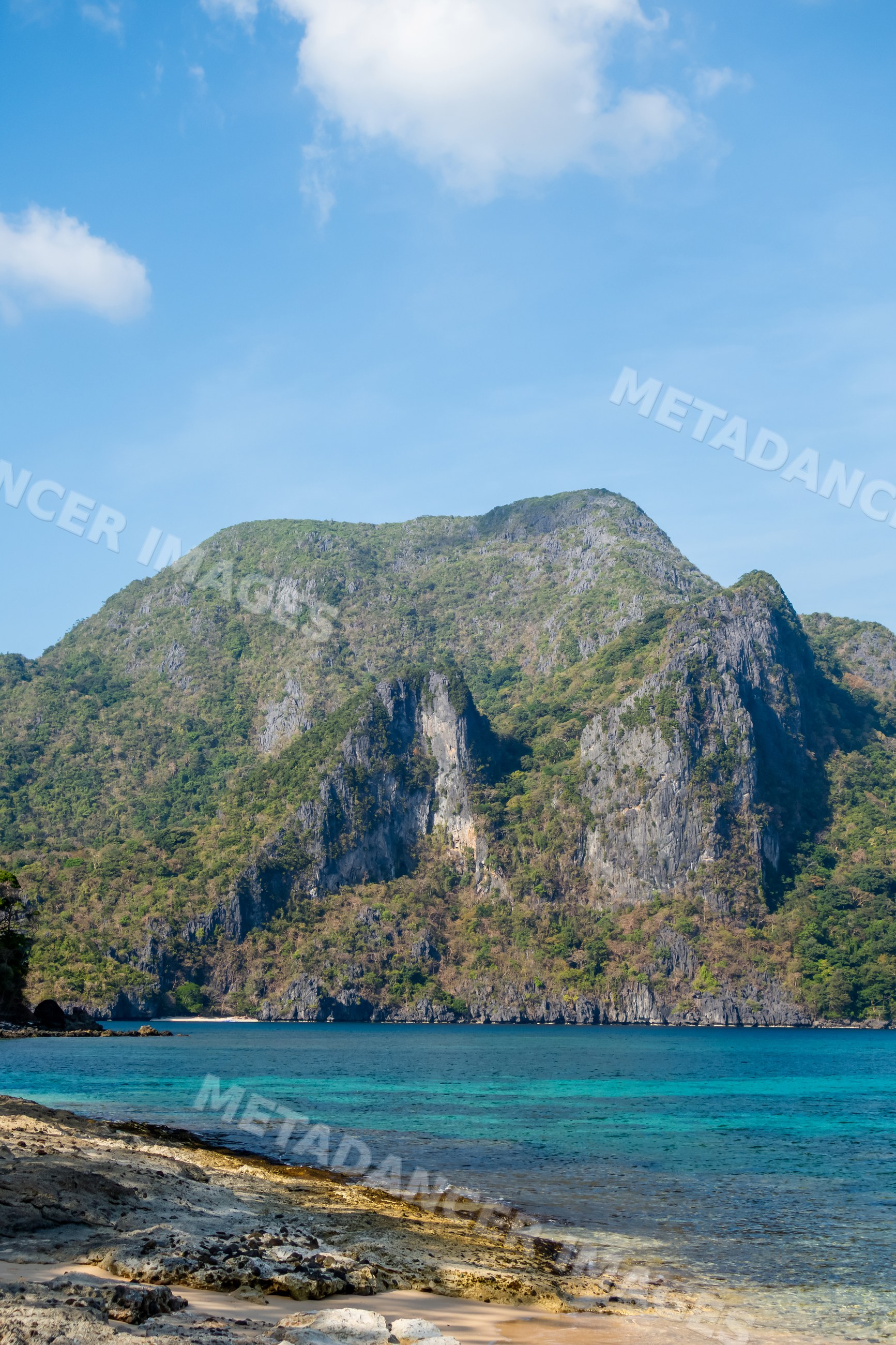 Rocky coastline and green mountain by ocean beach in a beach