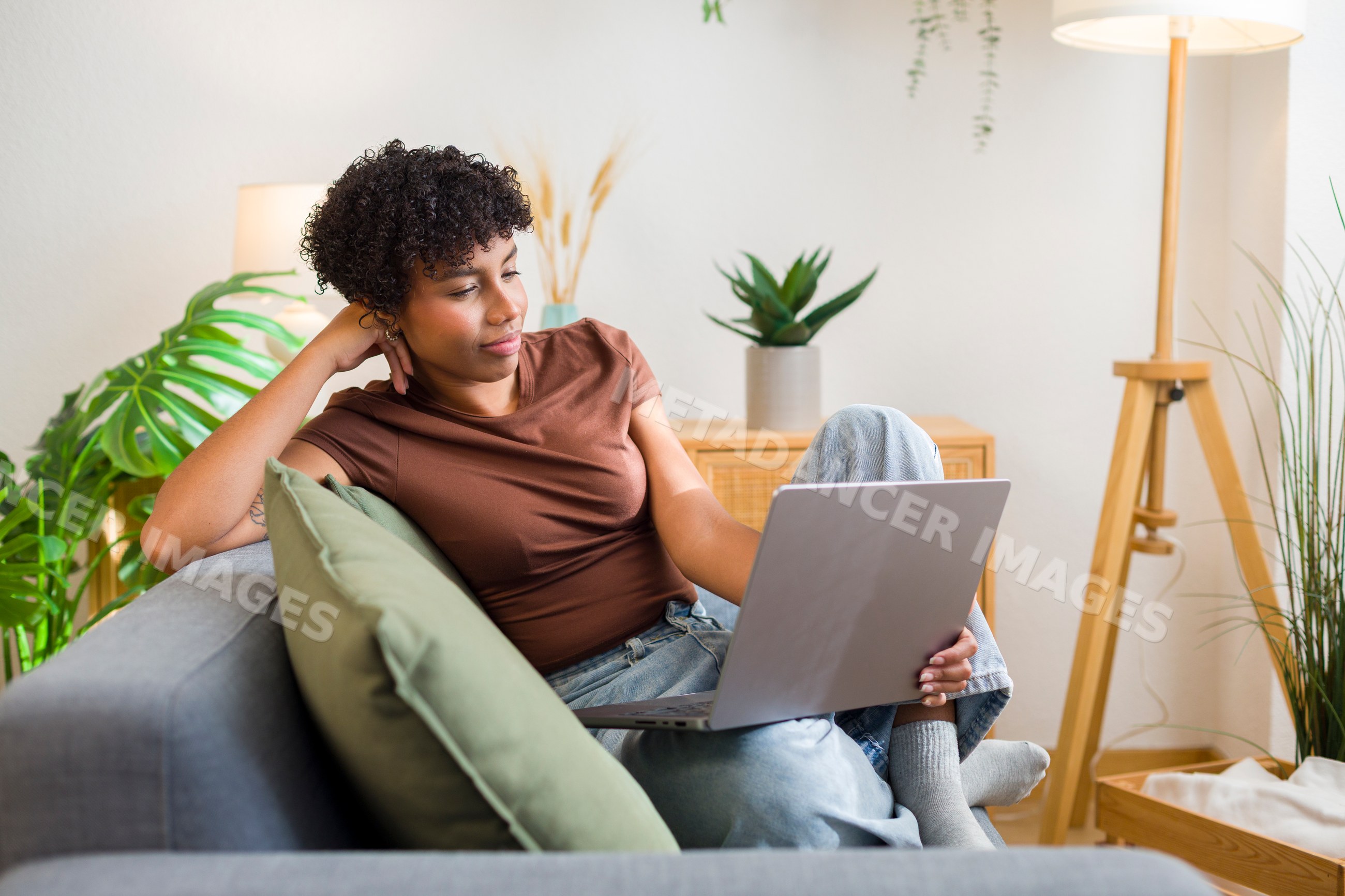 African American woman relaxing on sofa using laptop