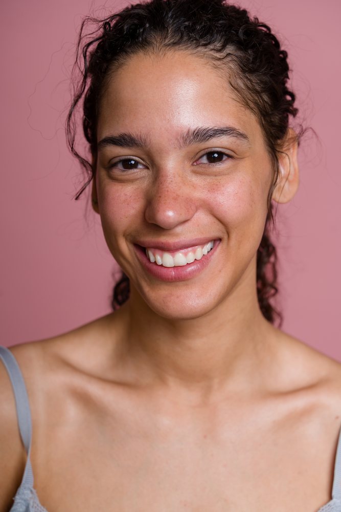 Young Hispanic woman smiling in a beauty shoot with pink background