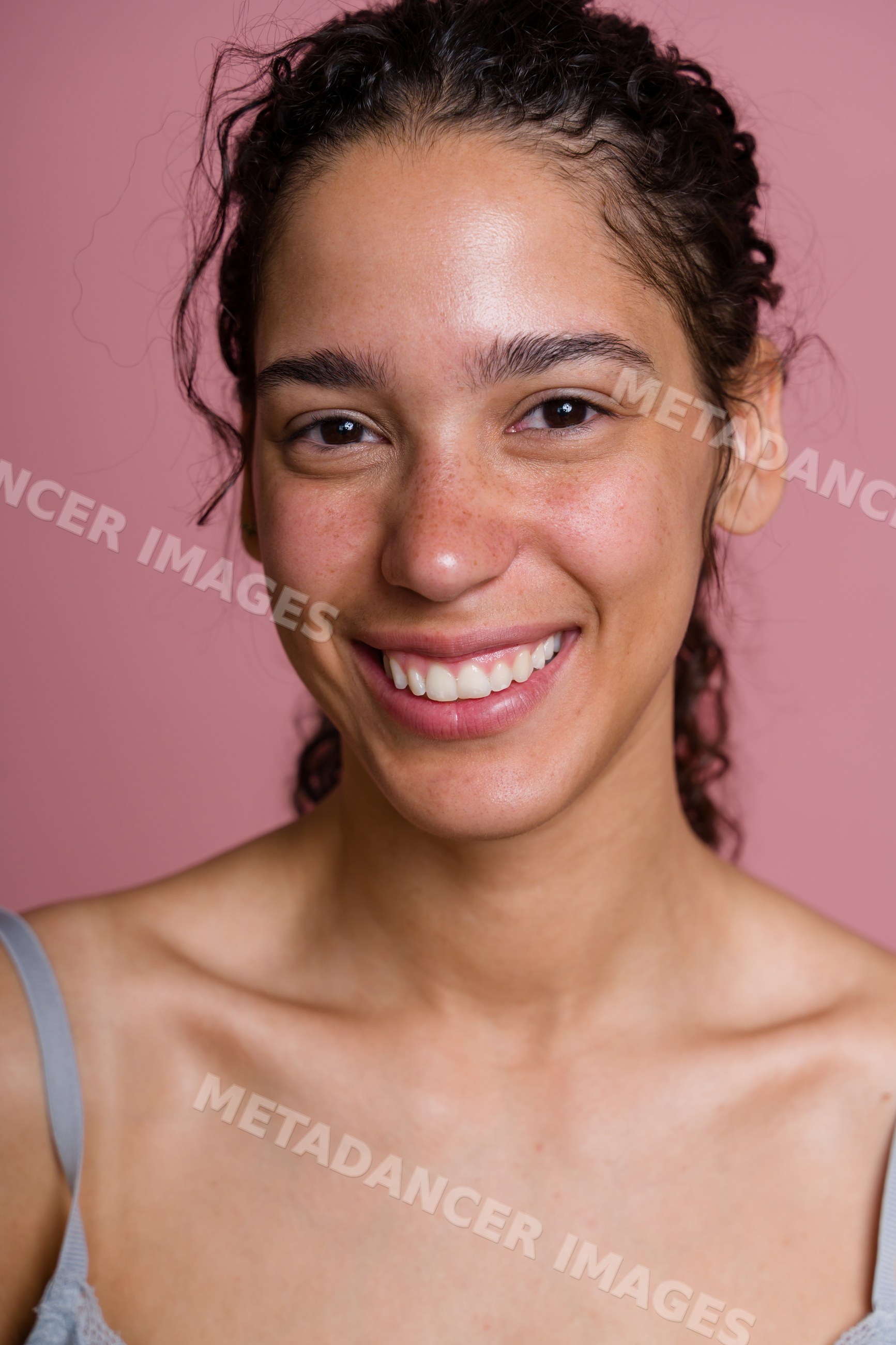 Young Hispanic woman smiling in a beauty shoot with pink background