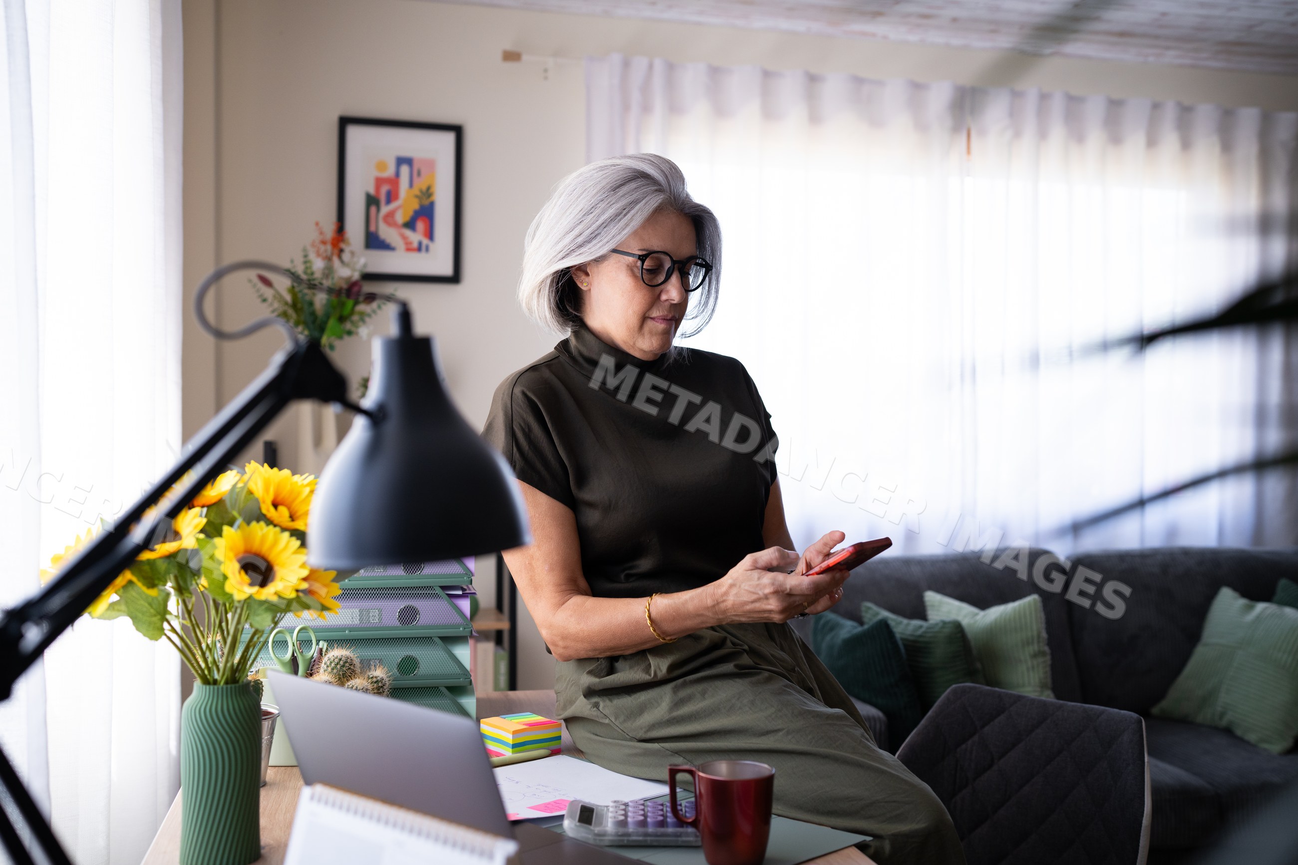 White woman using smartphone in modern home office living room