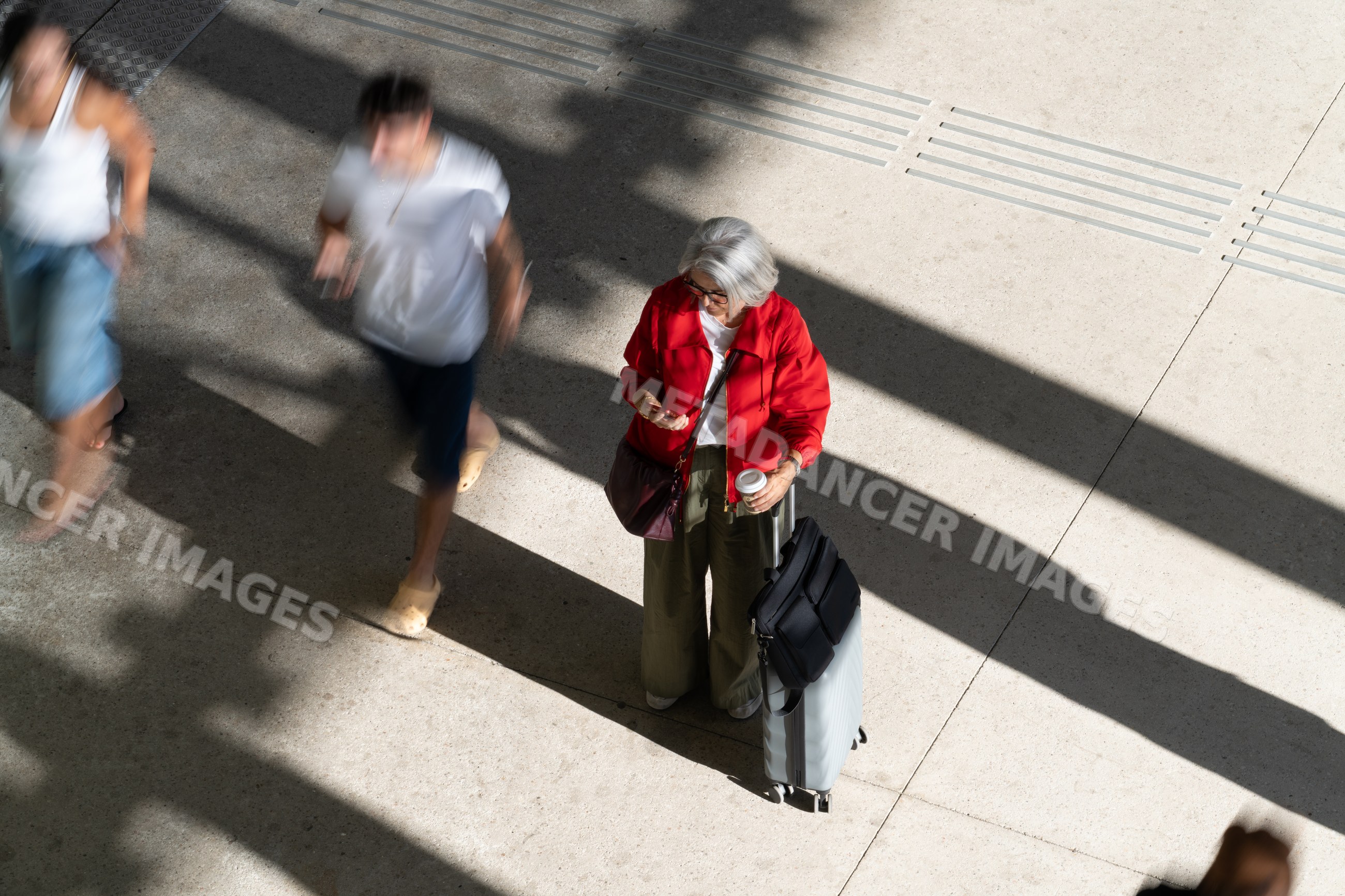 Older white woman standing with luggage and coffee