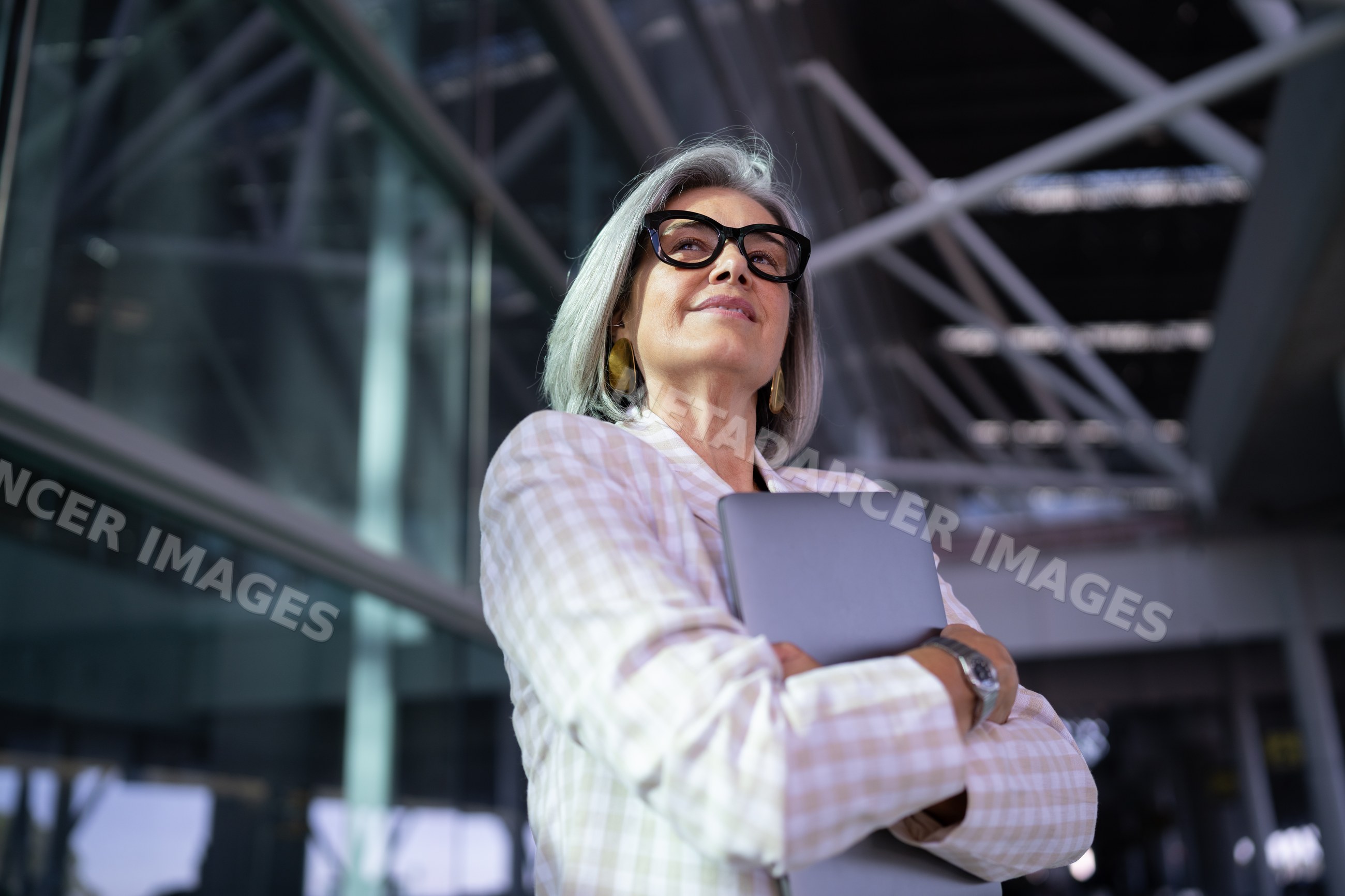 Businesswoman with gray hair holding tablet in modern building