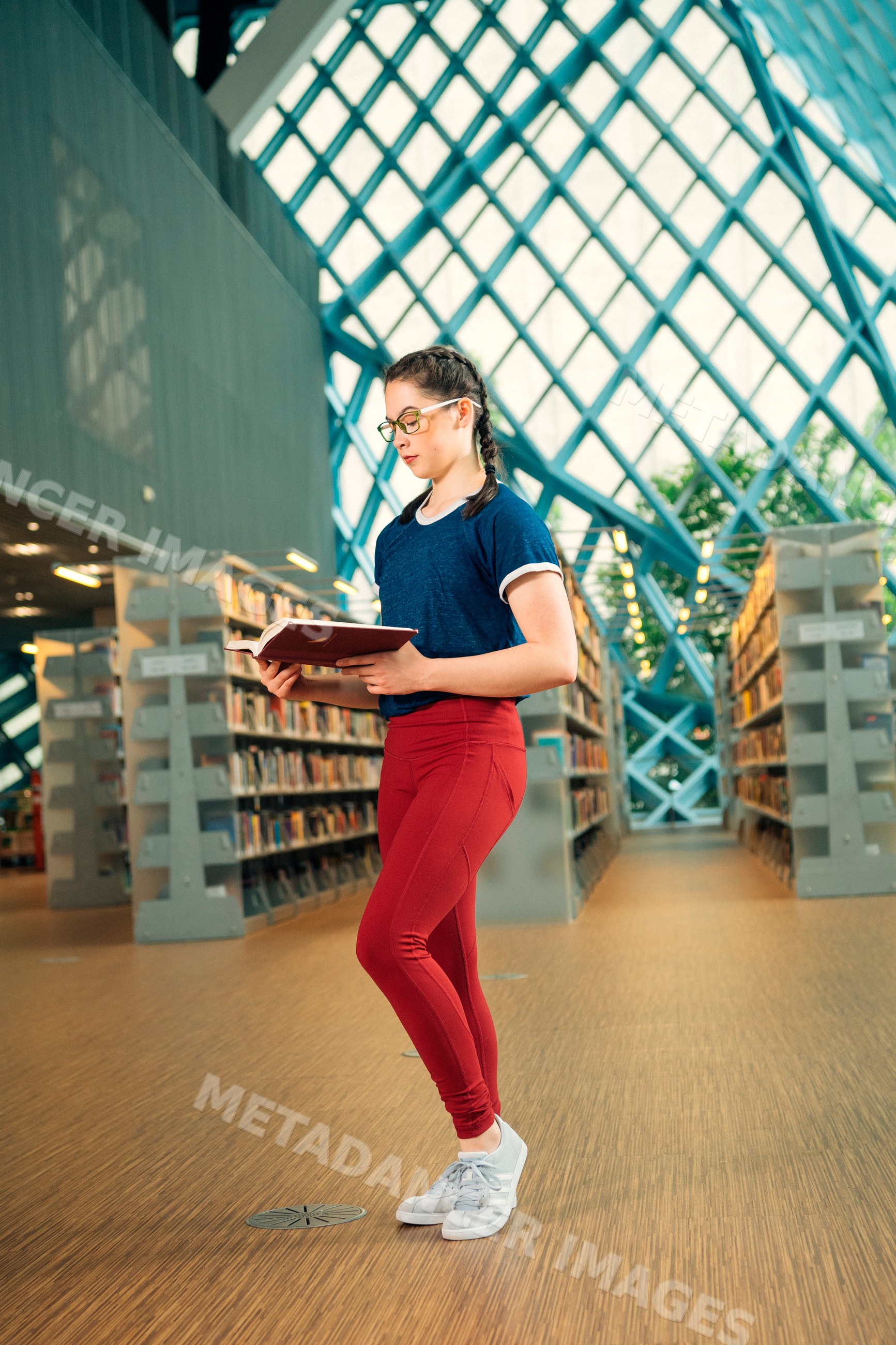 Teenage girl reading a book standing in a library