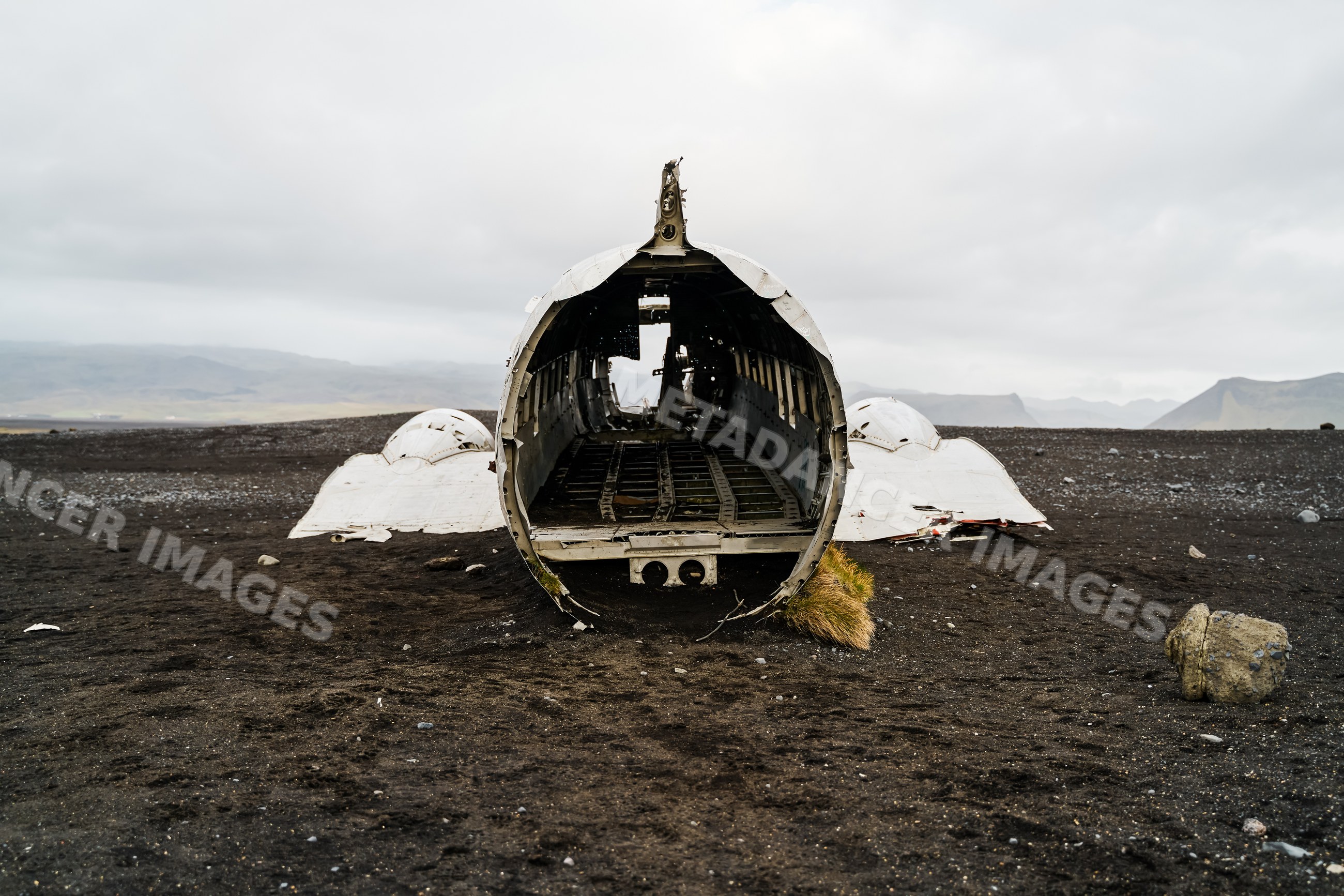 Abandoned airplane wreckage on black sandy terrain