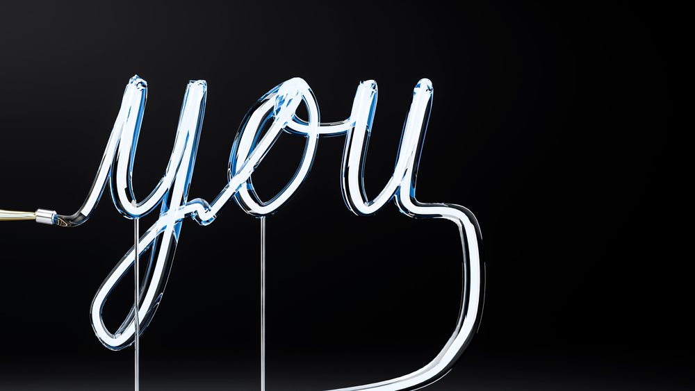 Neon sign glowing the word you in cursive lettering