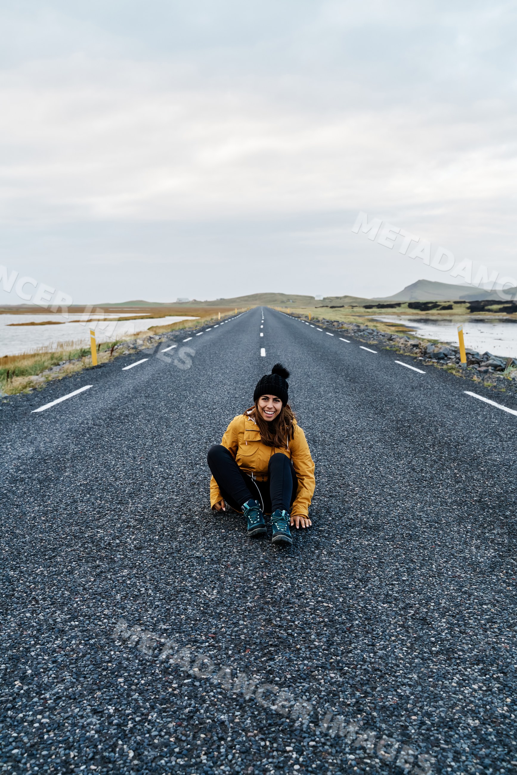 A white woman sitting and smiling on an empty road