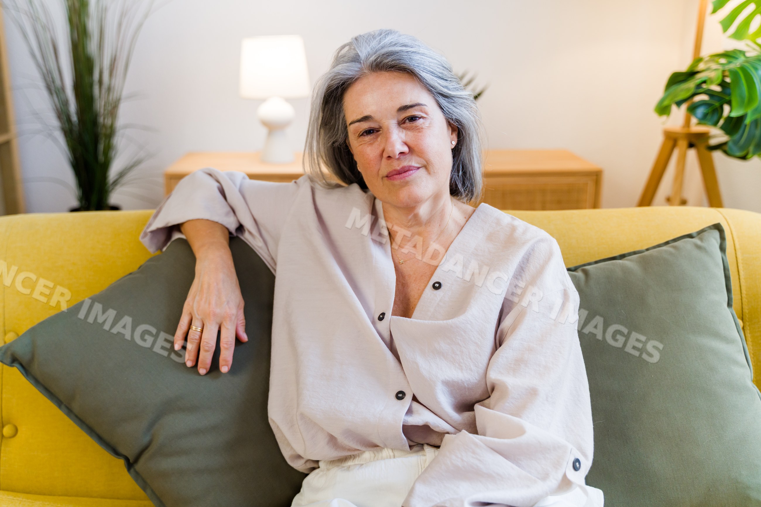 White woman sitting relaxed on yellow sofa in living room
