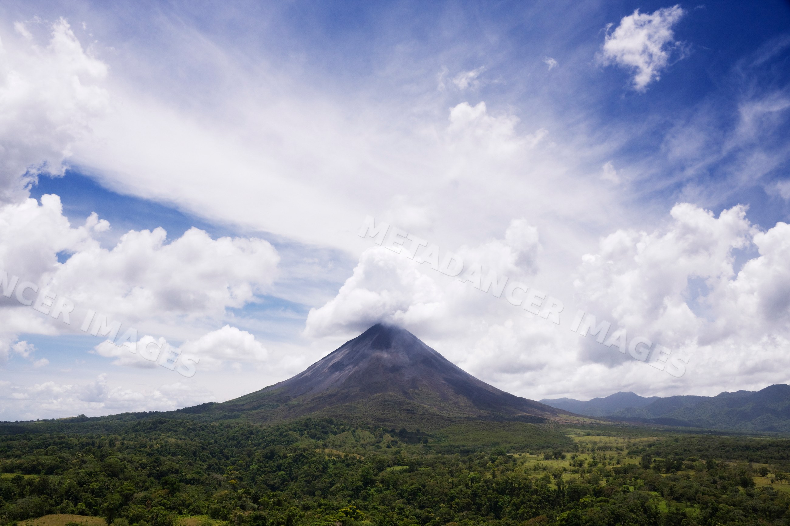 Arenal volcano rises above tropical forest landscape, costa rica