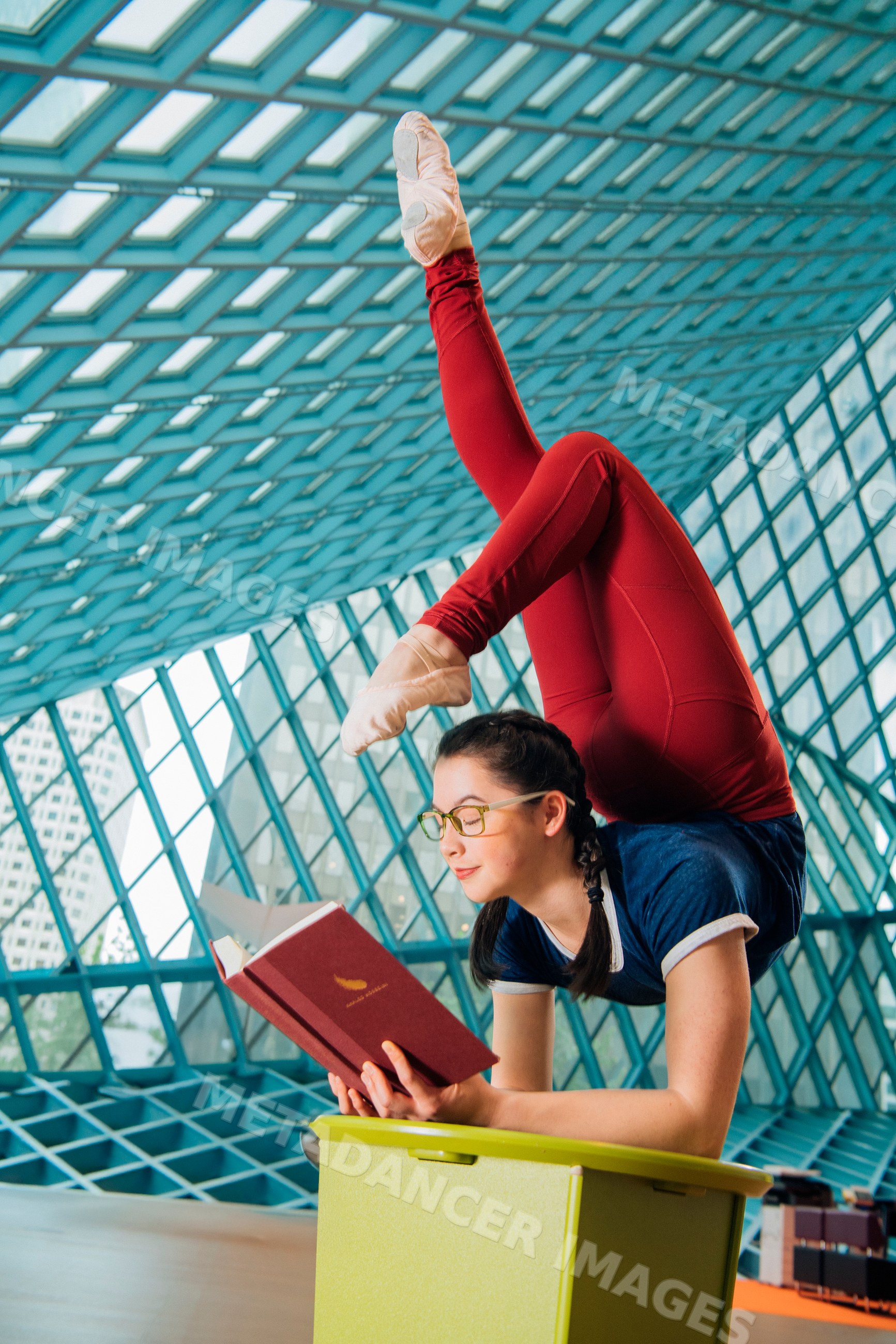 A young woman practices contortion while reading in a library