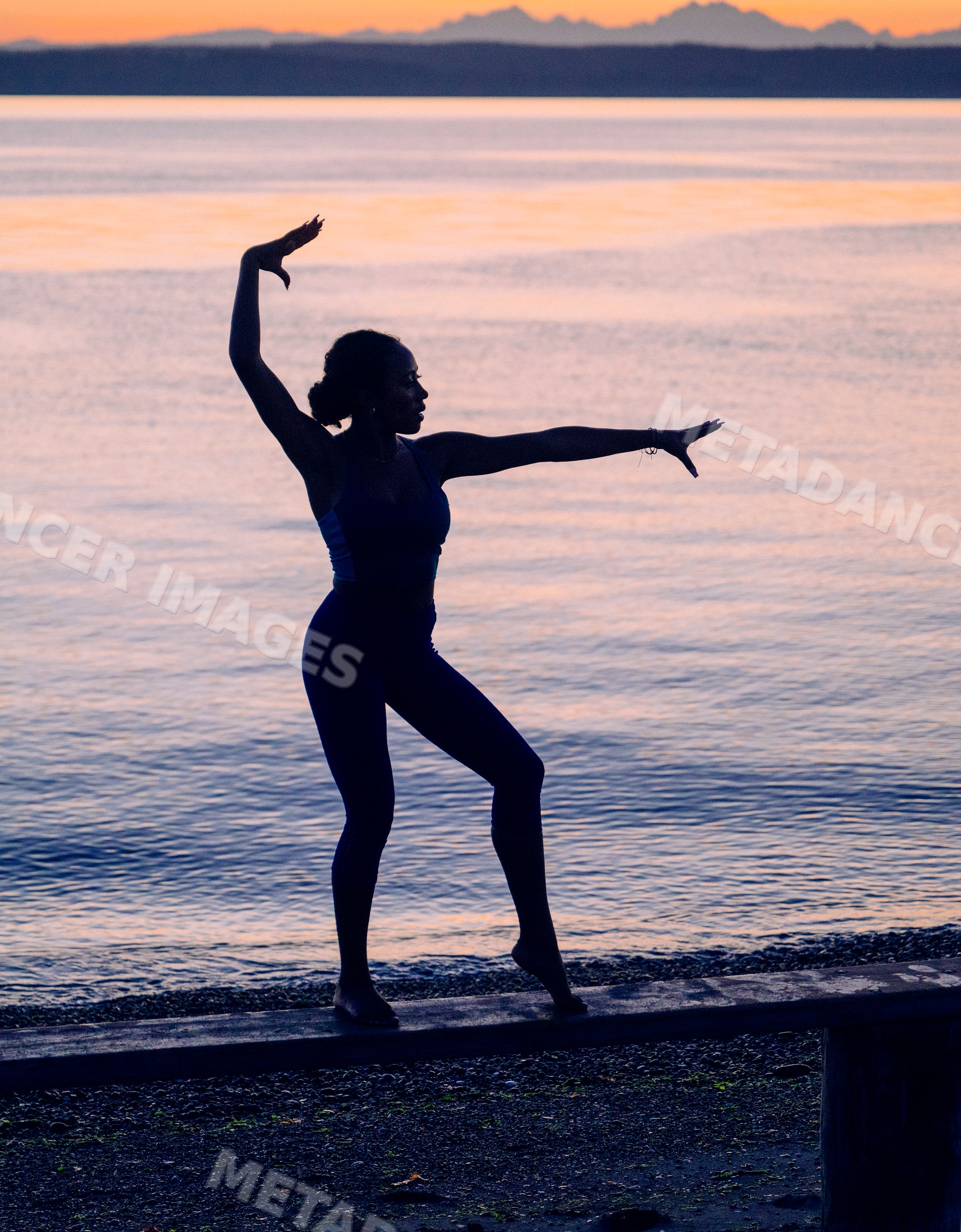 Hispanic woman practicing yoga acrobatics balancing at sunset by water