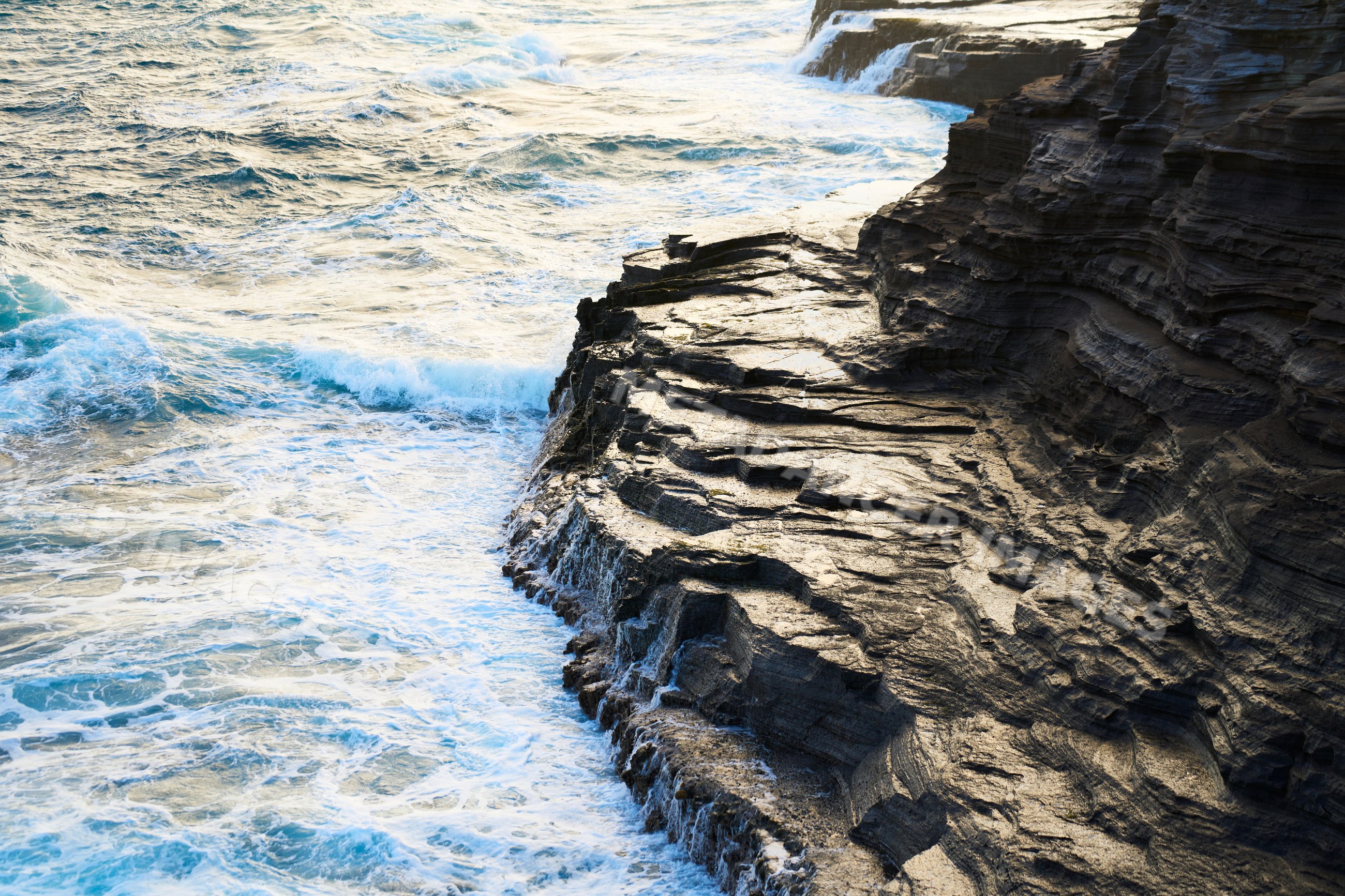 Ocean waves crashing on rocky cliff along Oahu coast
