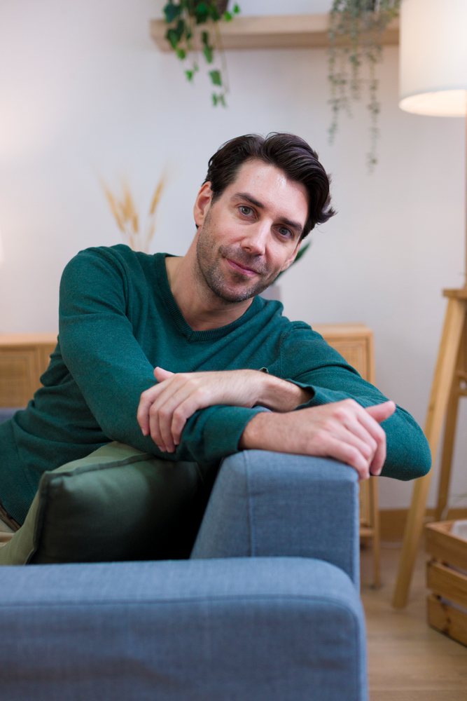 White man sitting relaxed on sofa in modern living room