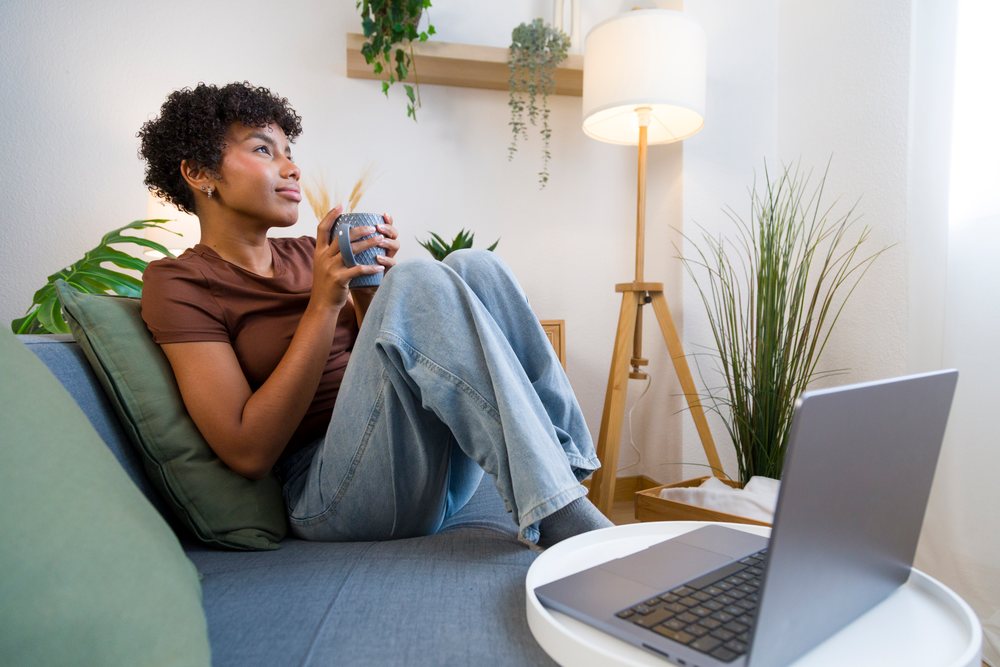 Young African American woman relaxing with coffee and laptop at home