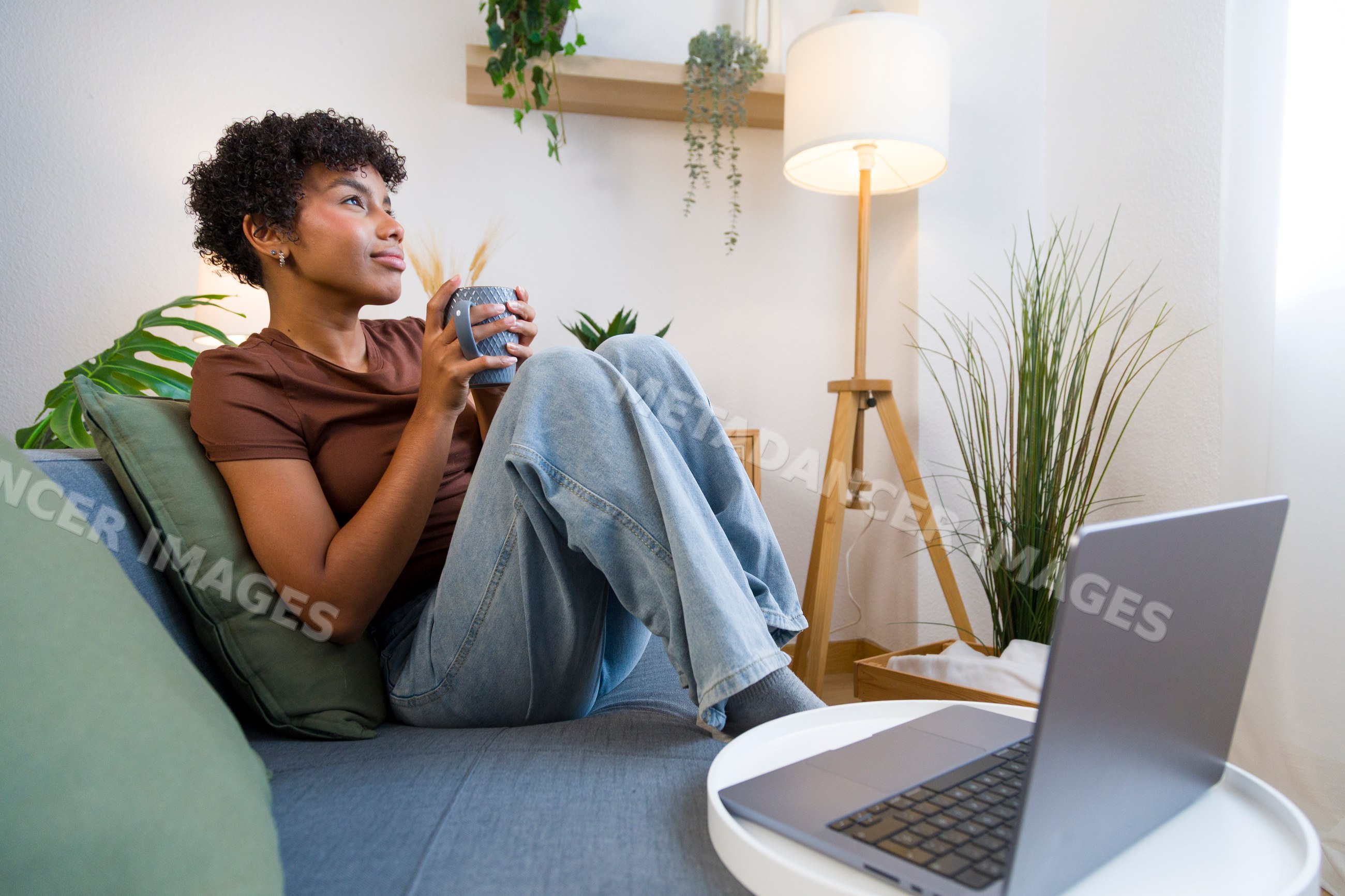 Young African American woman relaxing with coffee and laptop at home