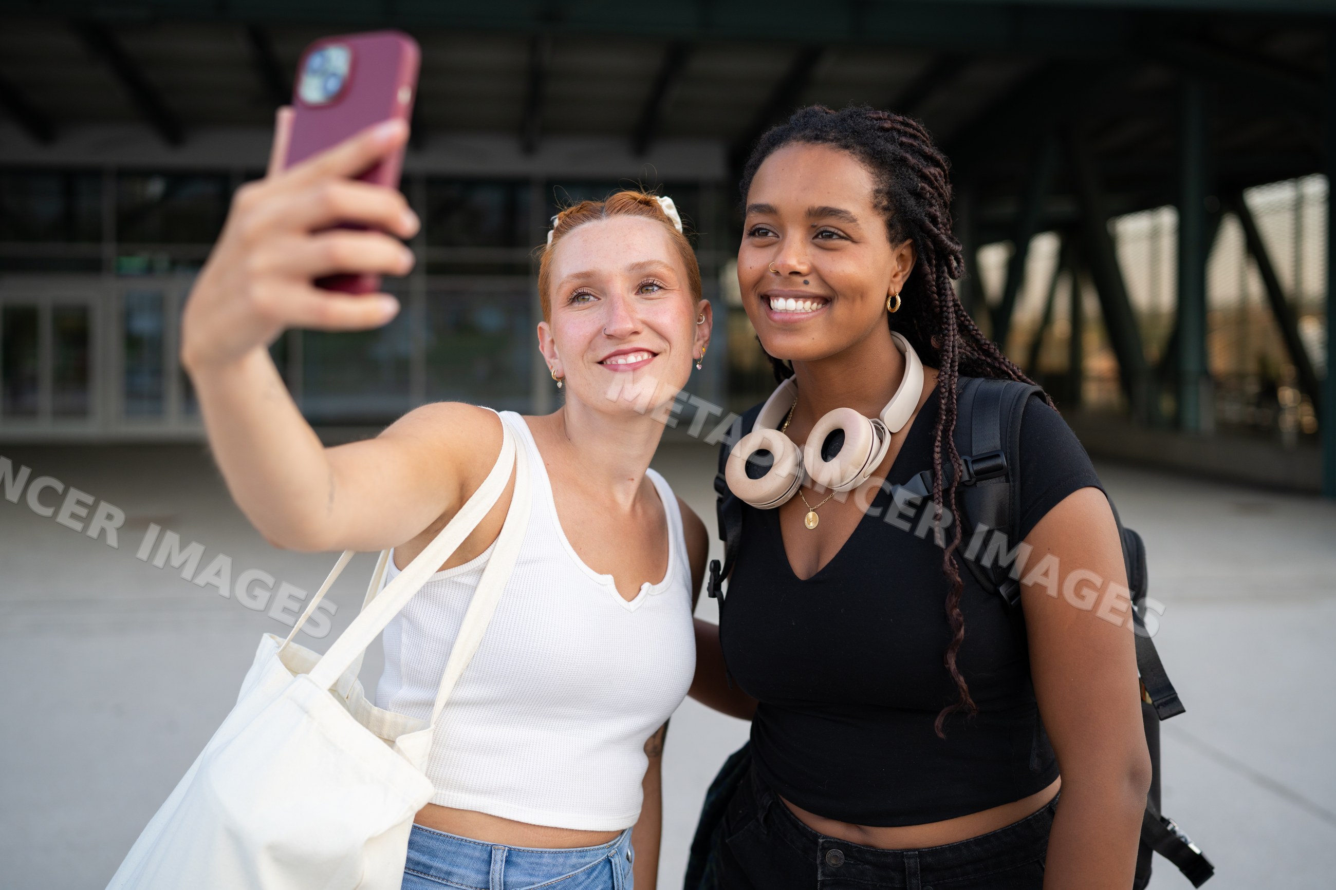 Two white and African American women smiling and taking a selfie