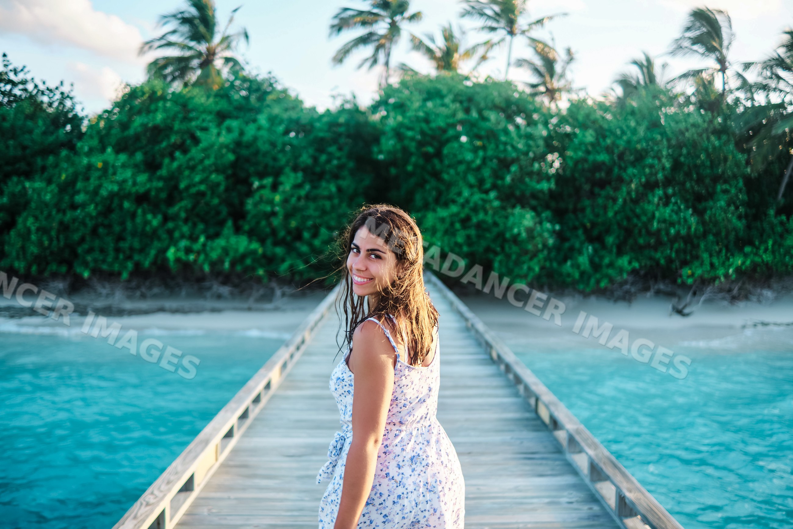 A young white woman walks and smiles on a pier