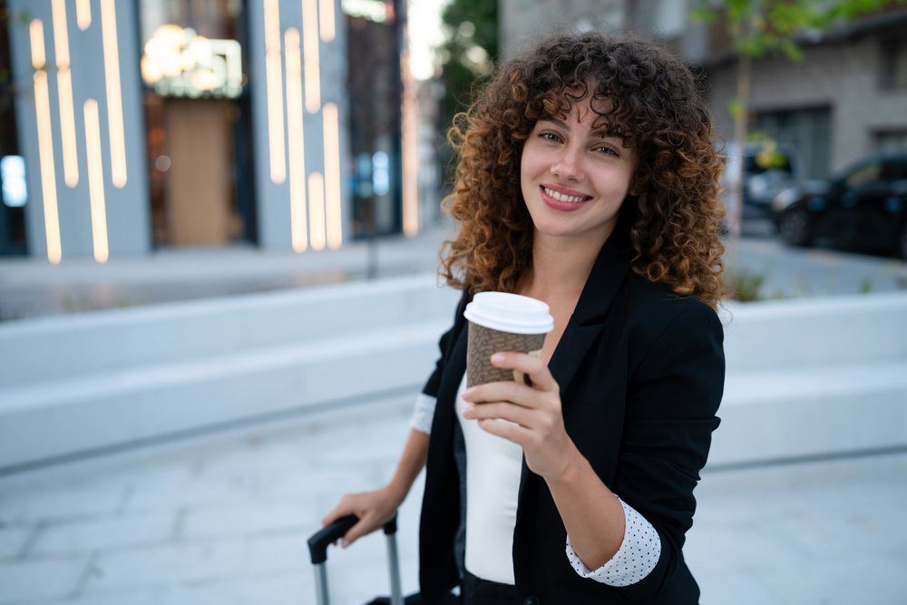 Young white woman holding to go coffee cup outdoors