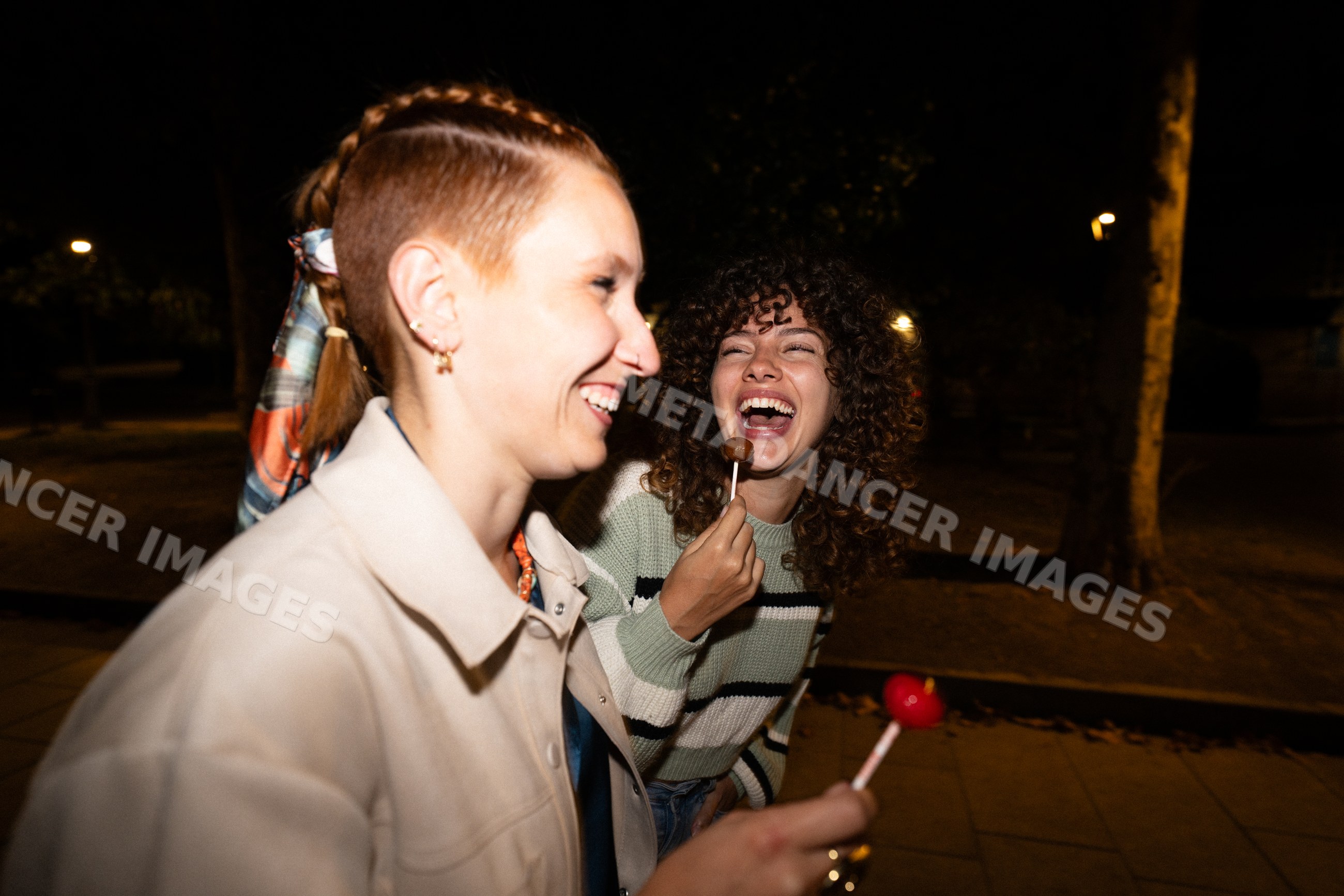 Two white women enjoying lollipops and laughing together
