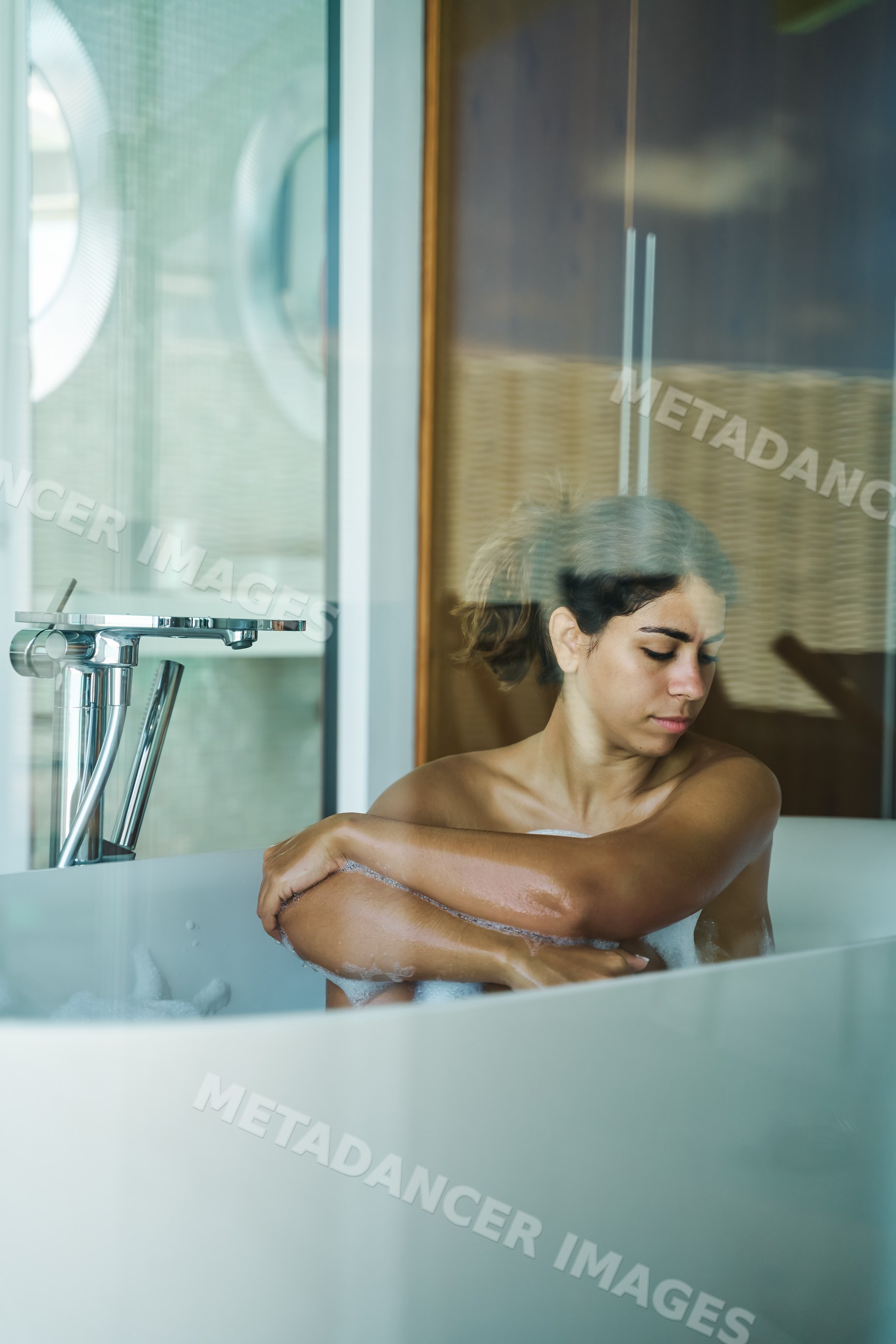 A white woman enjoys a relaxing bath in a modern bathroom
