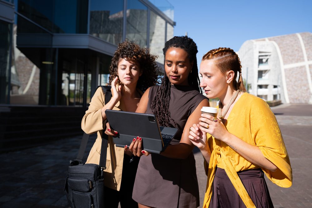 Three African American and white women collaborating with tablet