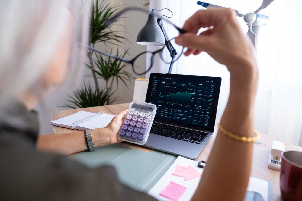 White person analyzing financial data on laptop with calculator