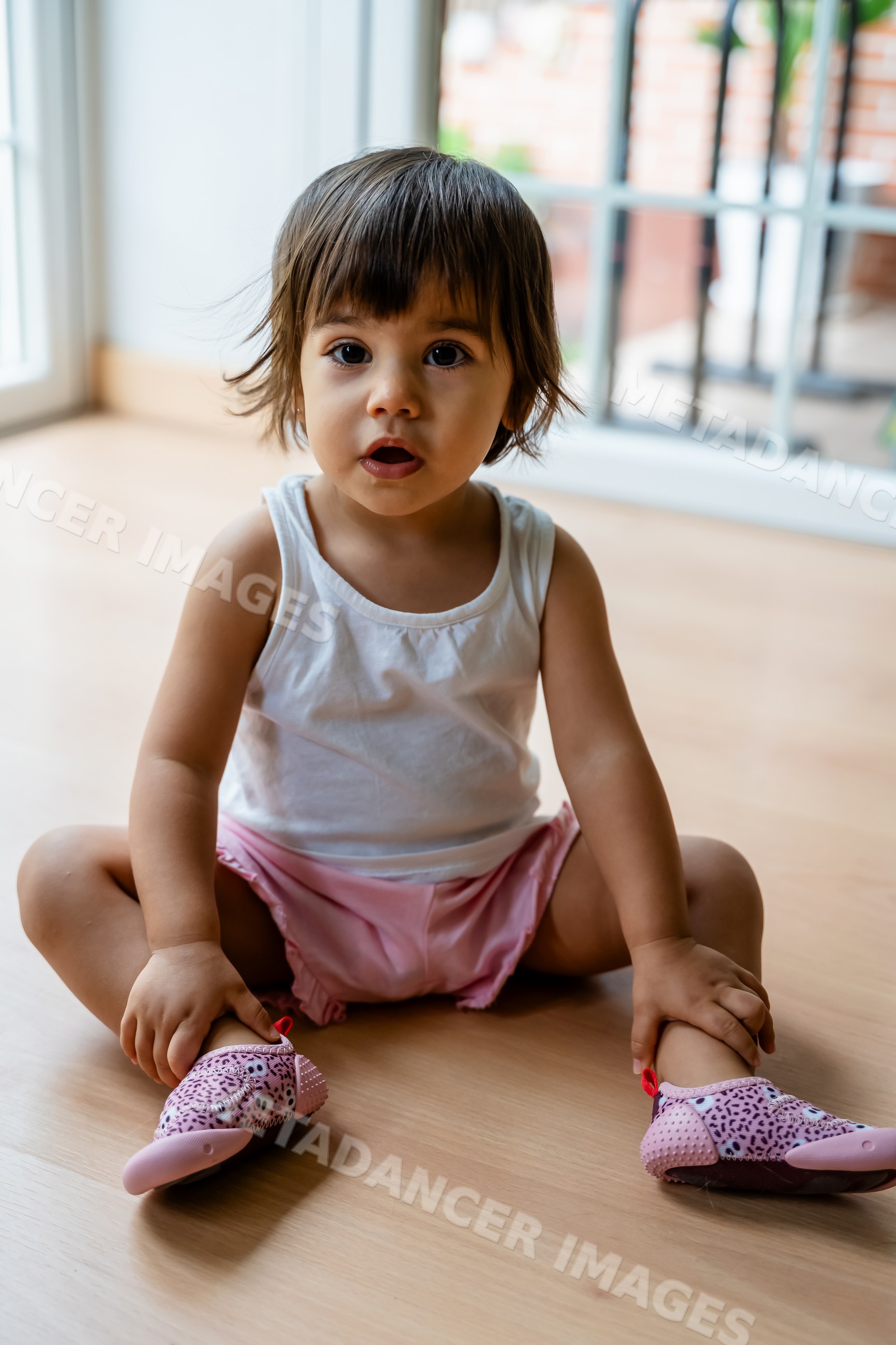 Toddler sitting on floor indoors near window in Spain