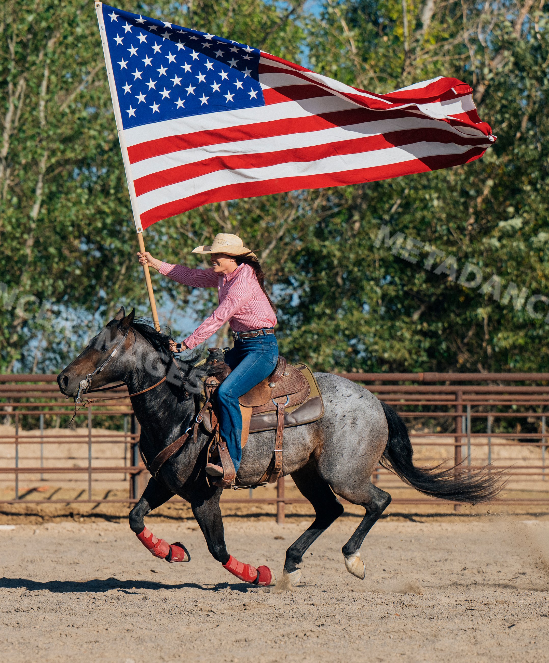 White woman riding horse holding american flag in rodeo arena