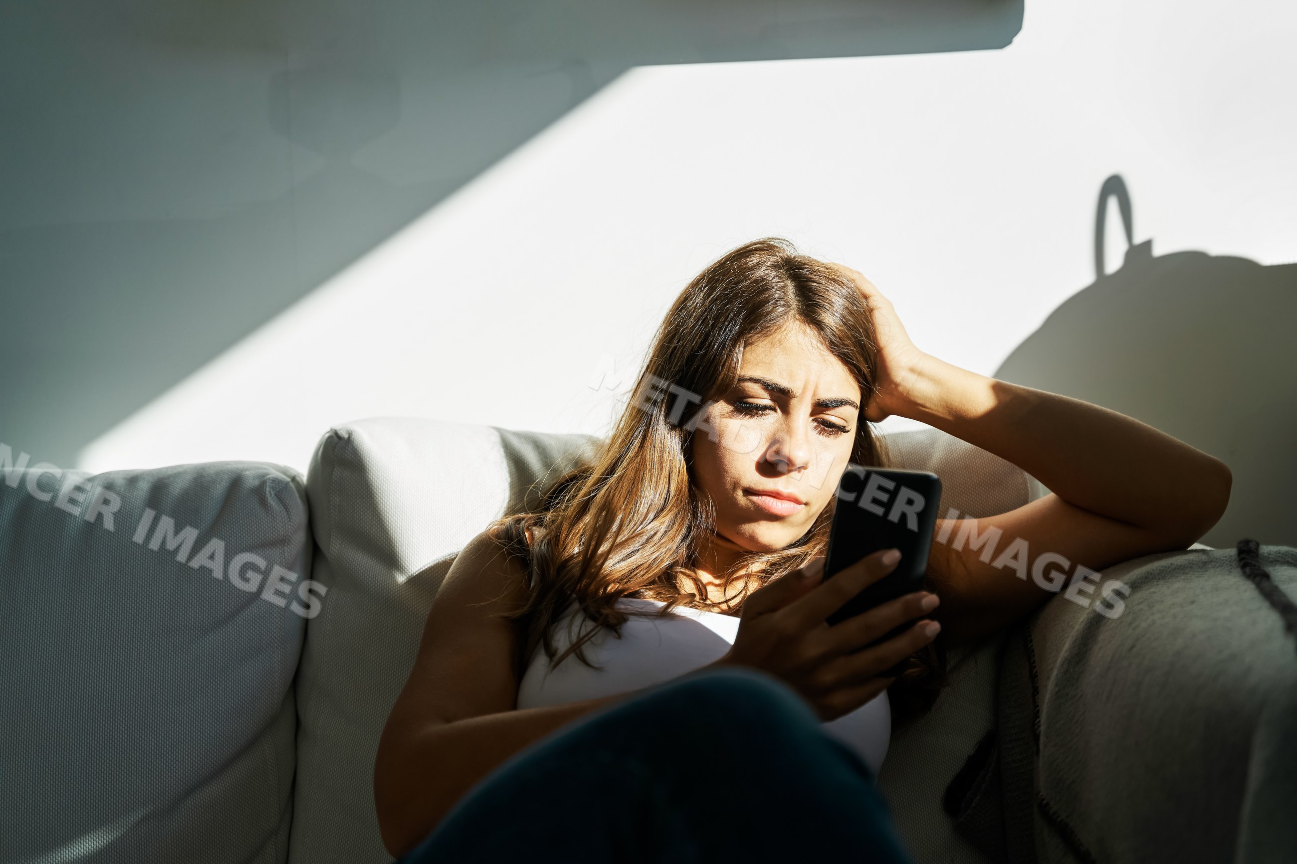 White Woman sitting on a sofa using a smartphone at home in Iceland